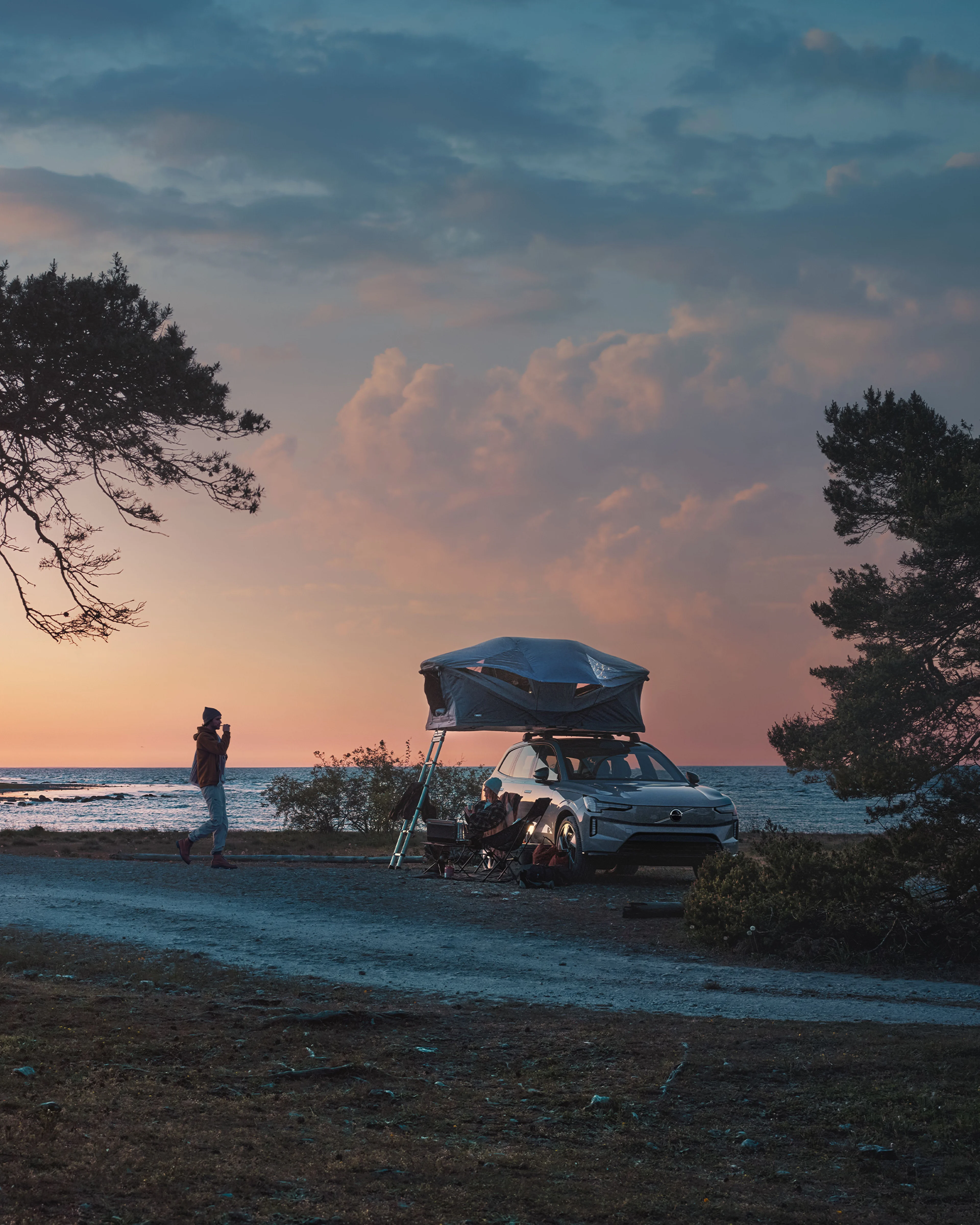 Volvo EX90 parkerad vid havet med ett taktält på taket.