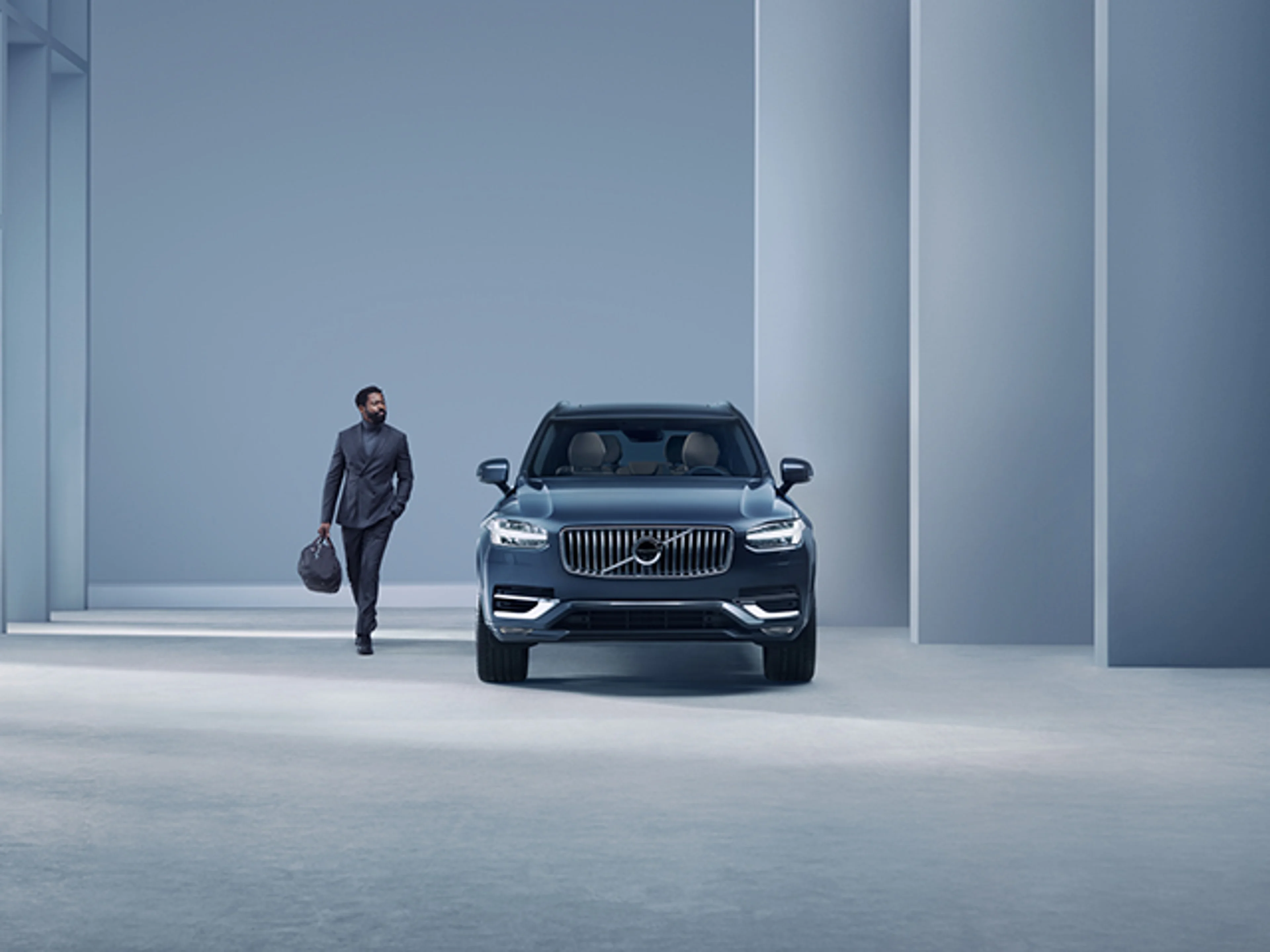 En man som står bredvid en blå Volvo XC90