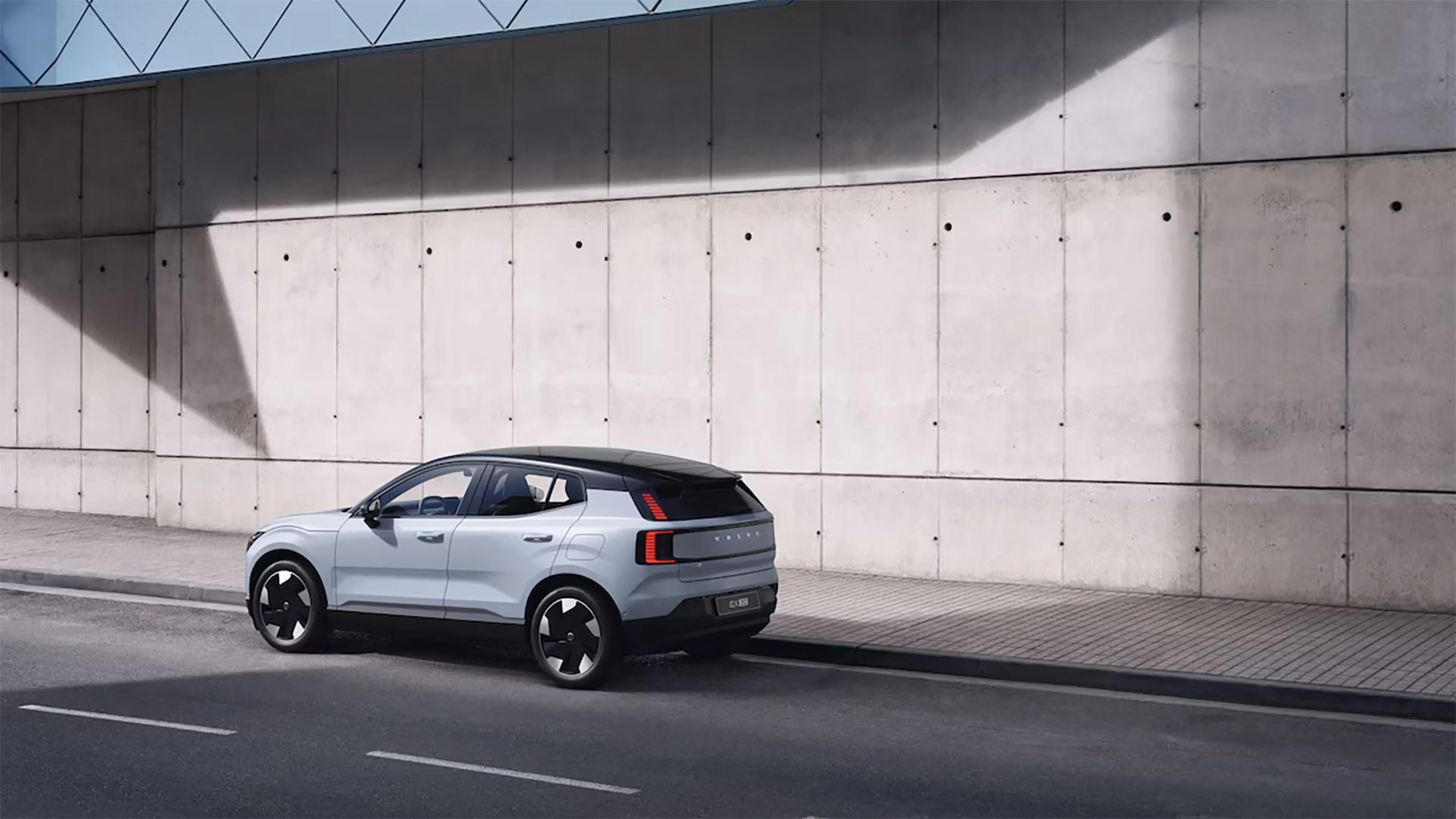 Volvo EX30 blanc garé en bord de rue avec un mur en béton en arrière-plan