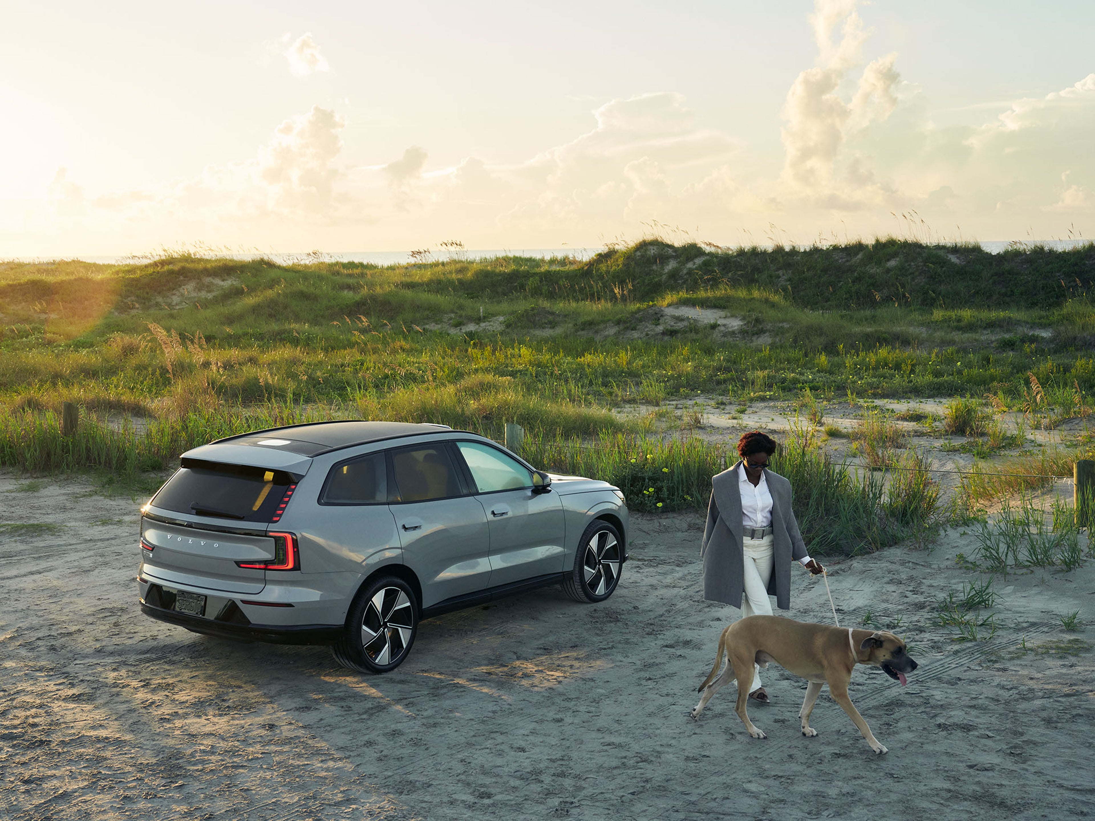 Woman walking dog next to Volvo EX90 SUV