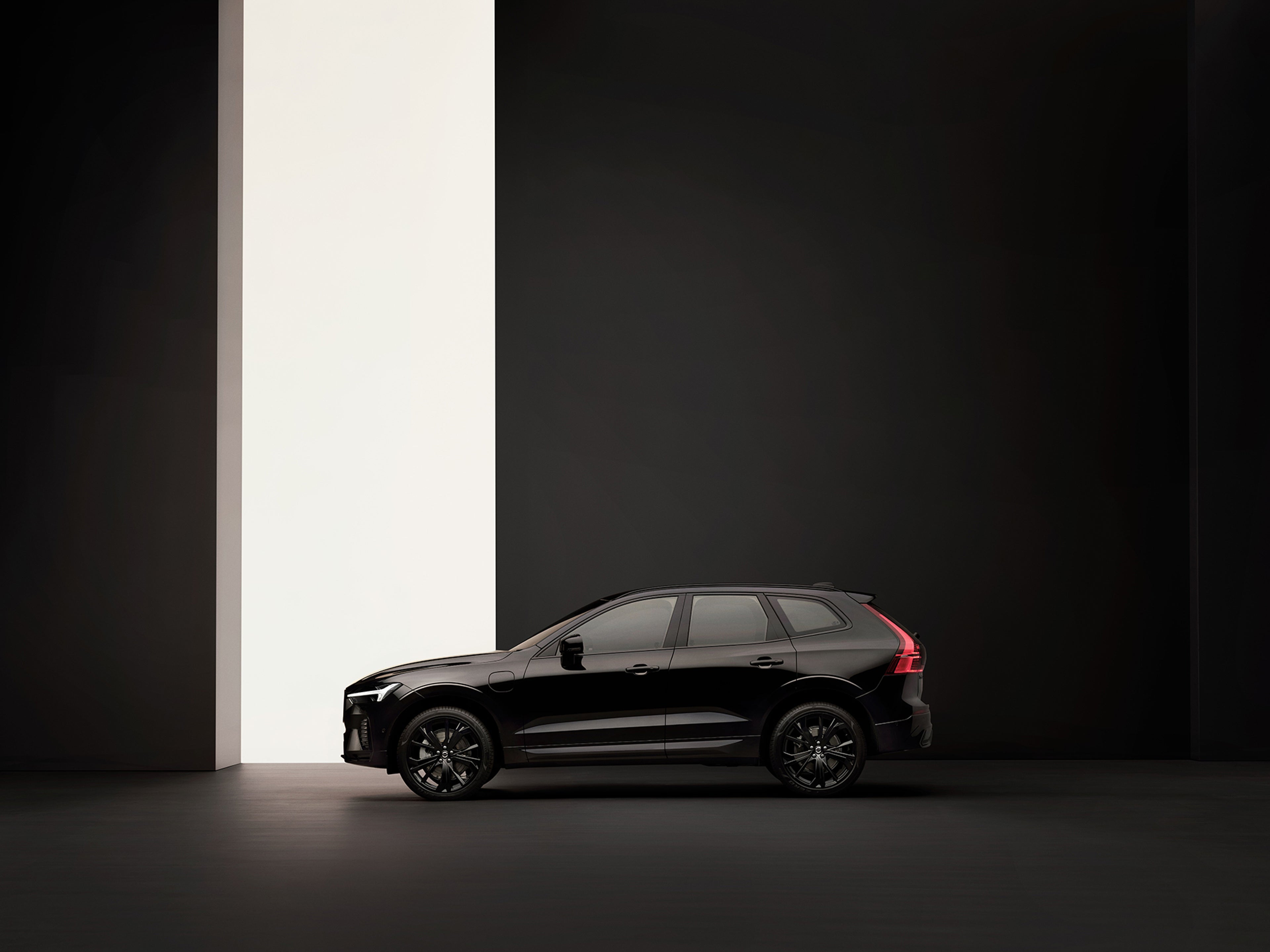 XC60 black edition de perfil, num estudio preto com uma abertura lateral