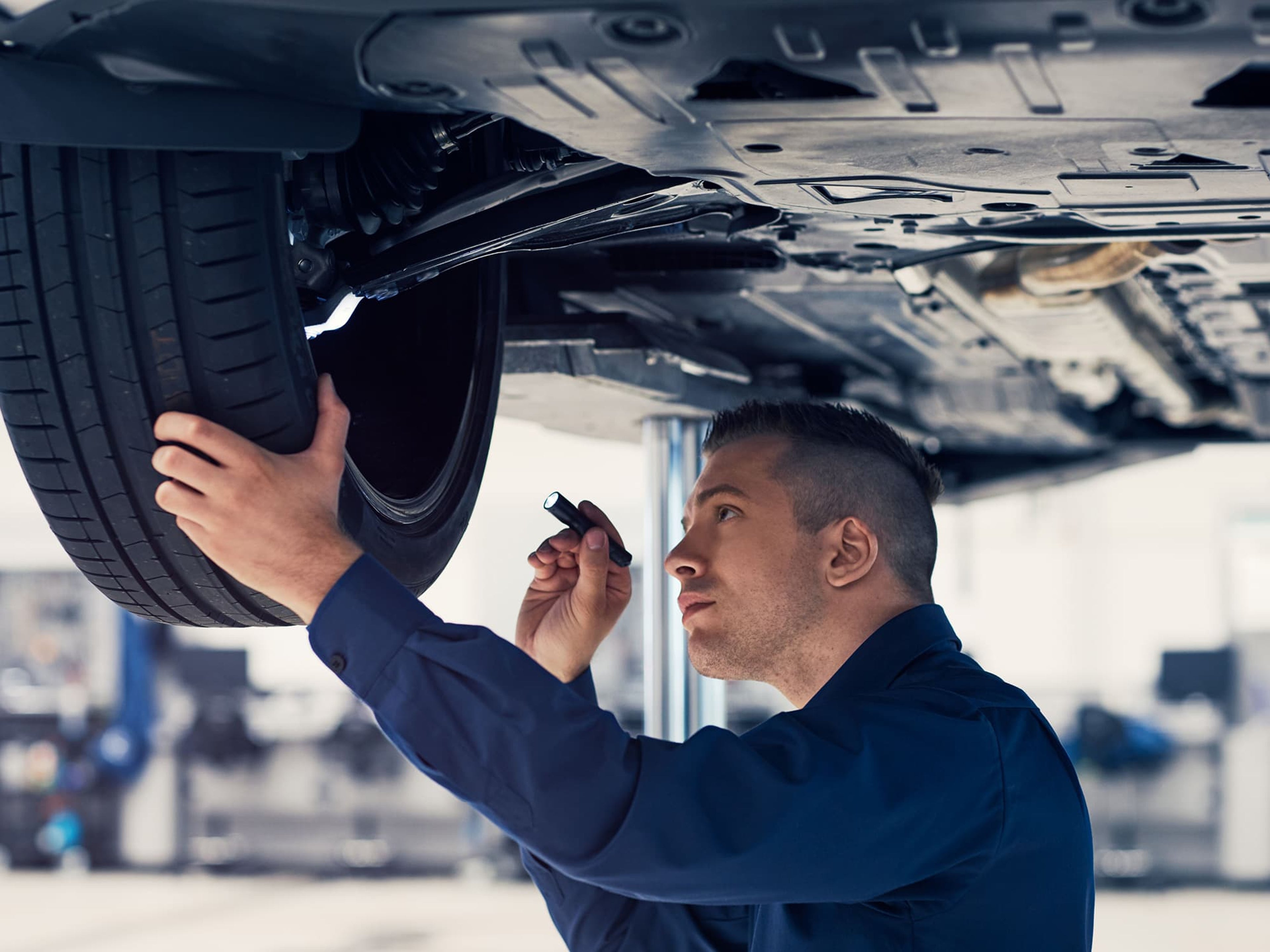 Een Volvo-technieker inspecteert een band onder een Volvo op een lift.