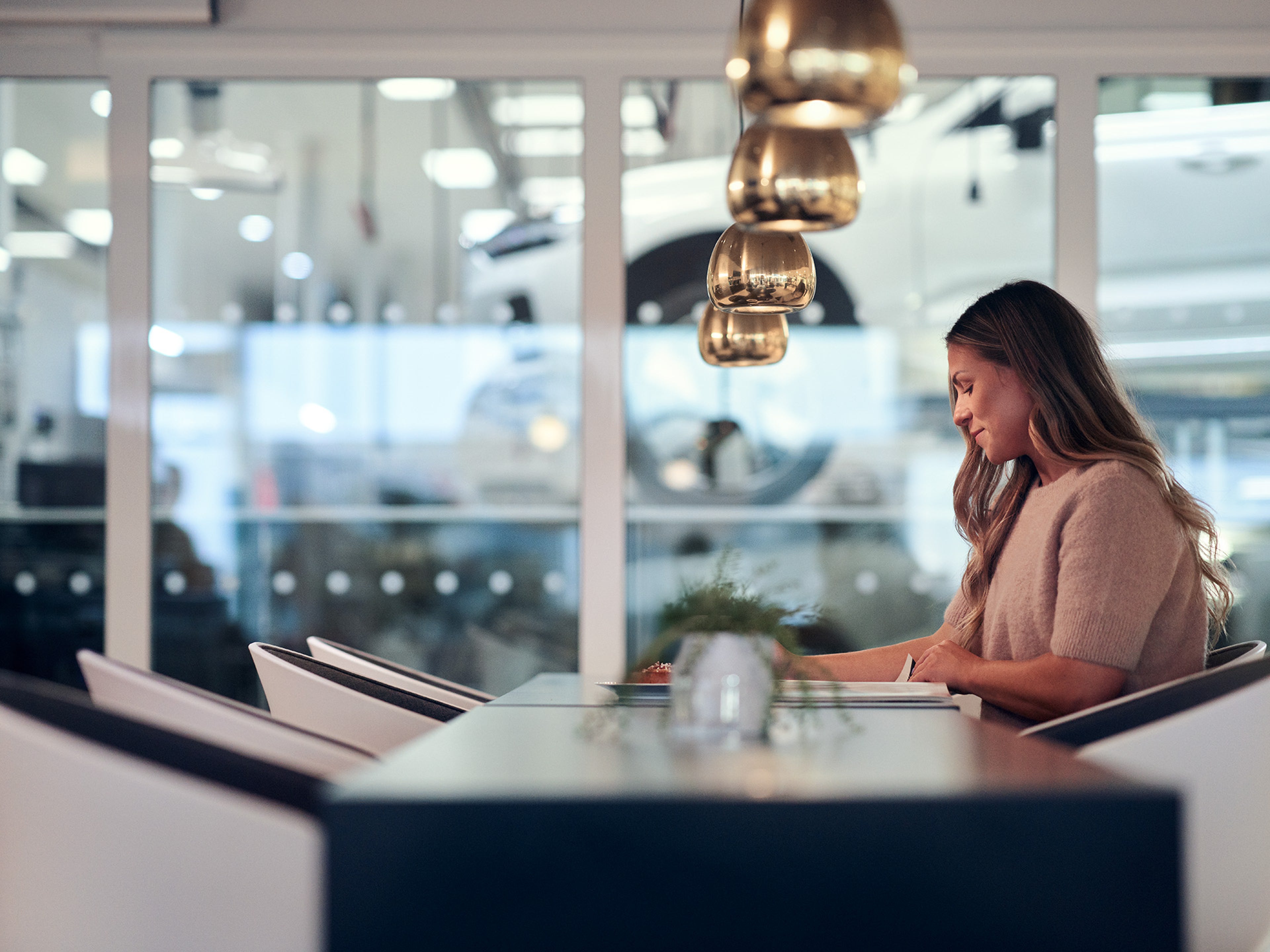 Mulher sentada à mesa num ambiente moderno lendo um documento.