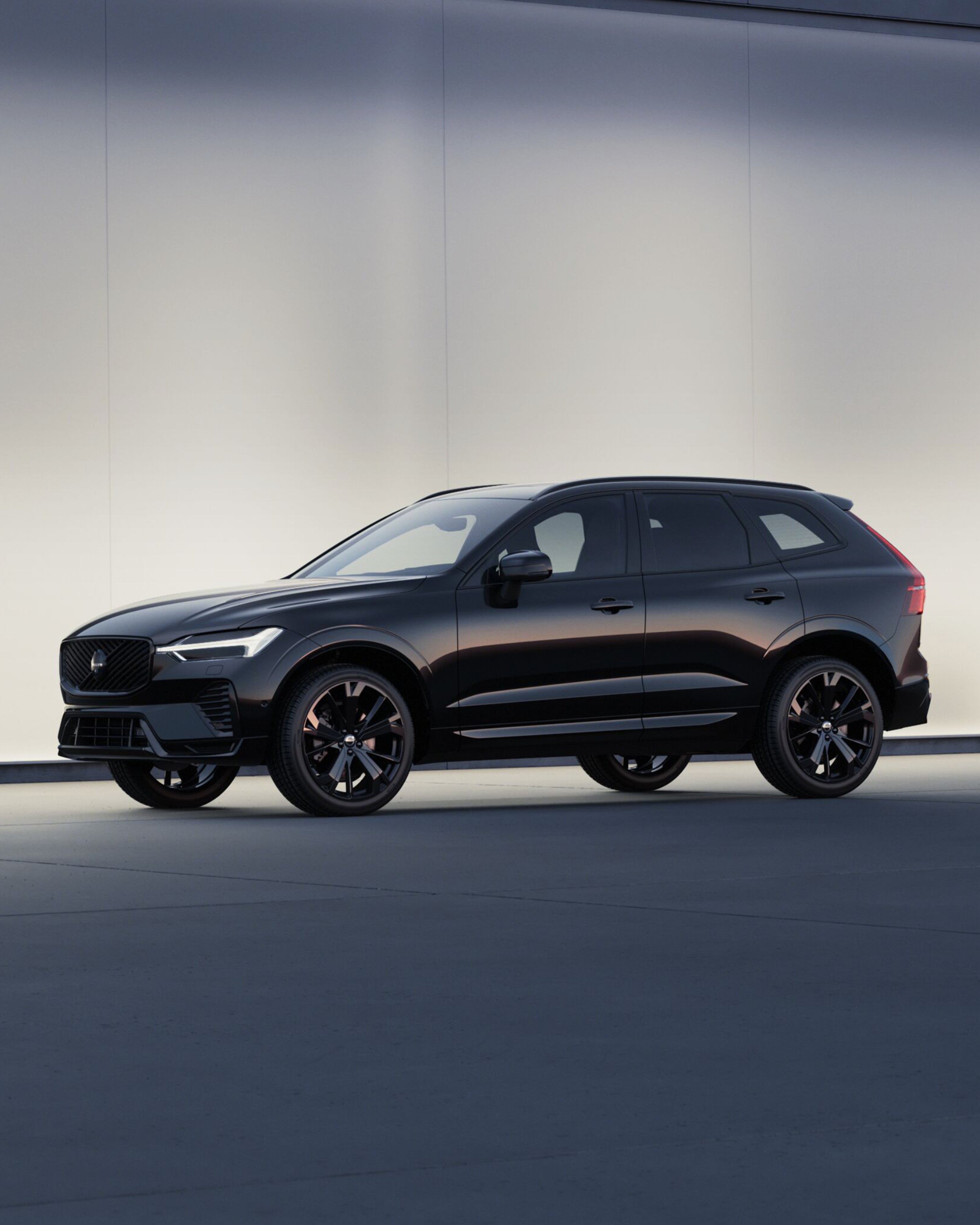 Seitenansicht eines schwarzen Volvo XC60 vor einer hellen Steinwand.
