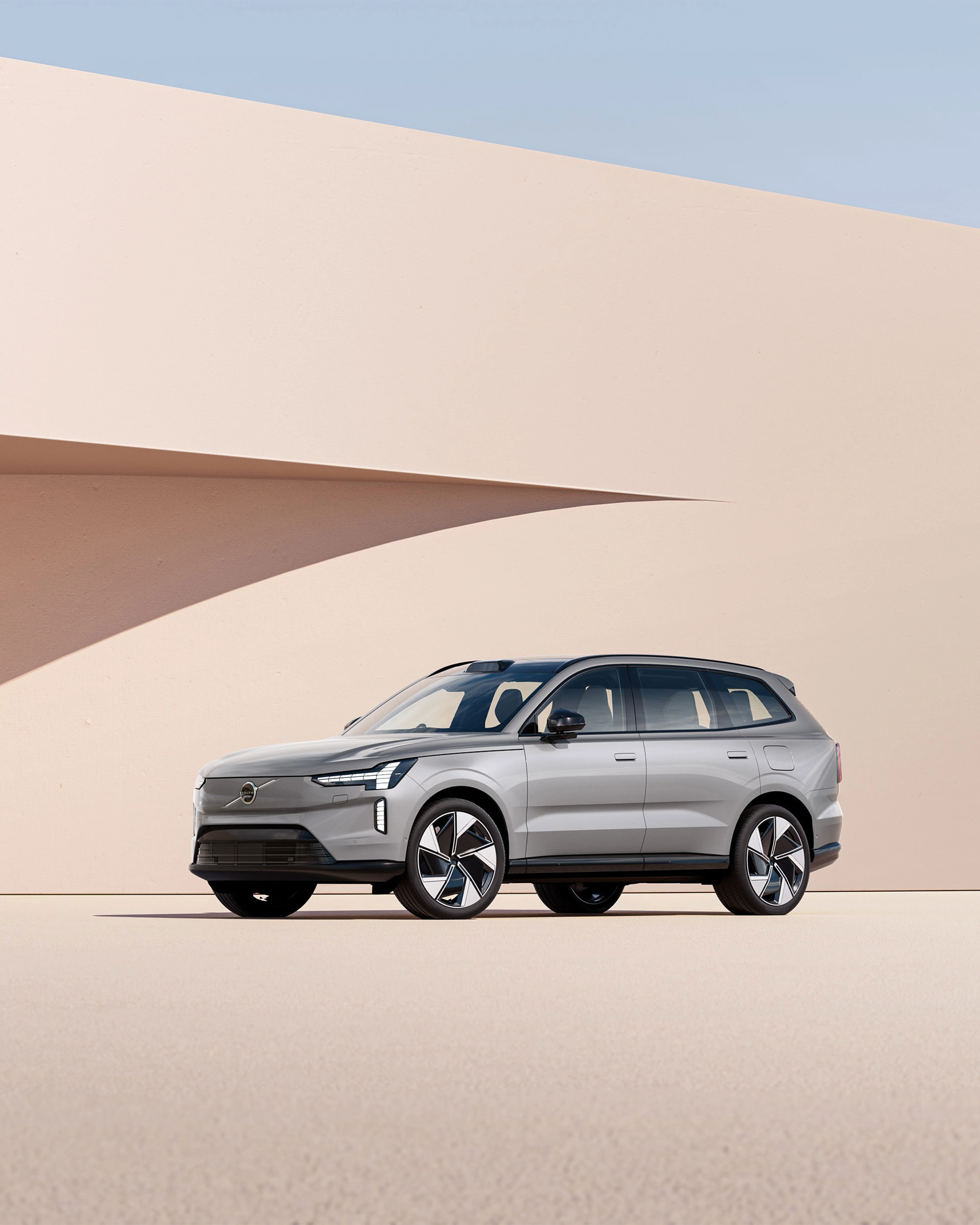Volvo EX90 argenté garé devant un mur beige avec une ombre projetée