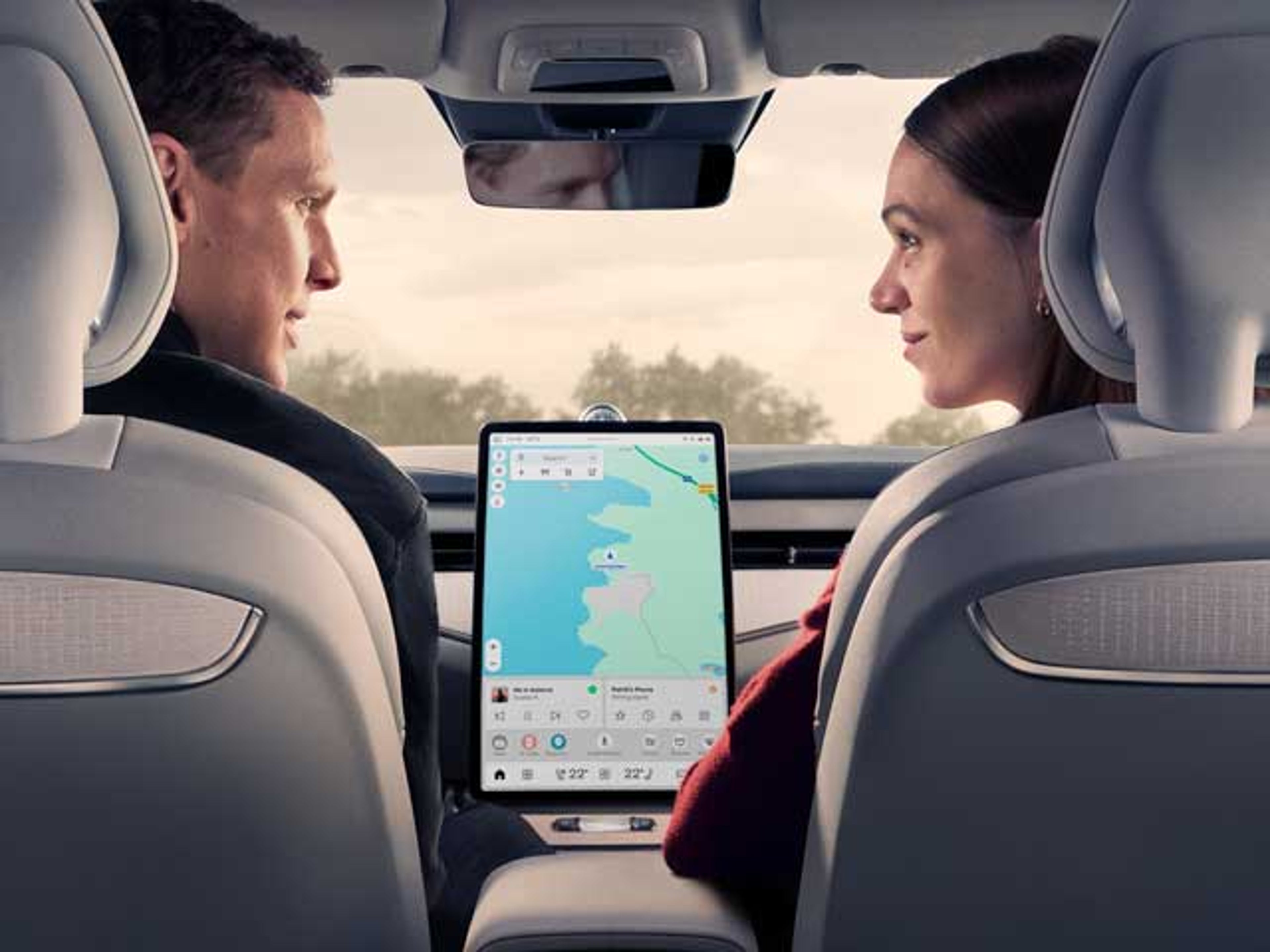 Una pareja mirándose dentro del habitáculo de un vehículo Volvo y una pantalla central en el medio