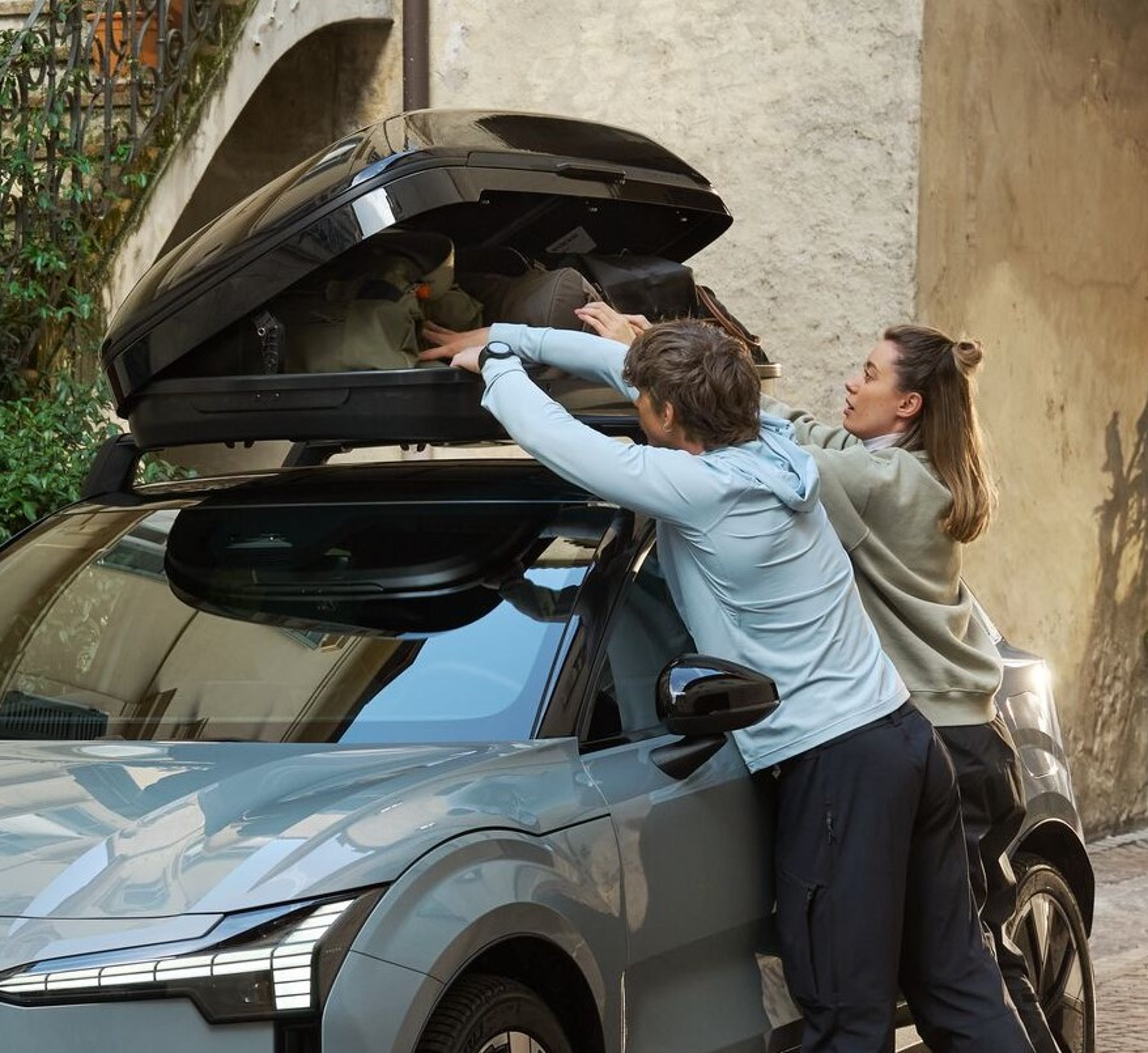 Kvinna stänger en takbox monterad på en Volvo.