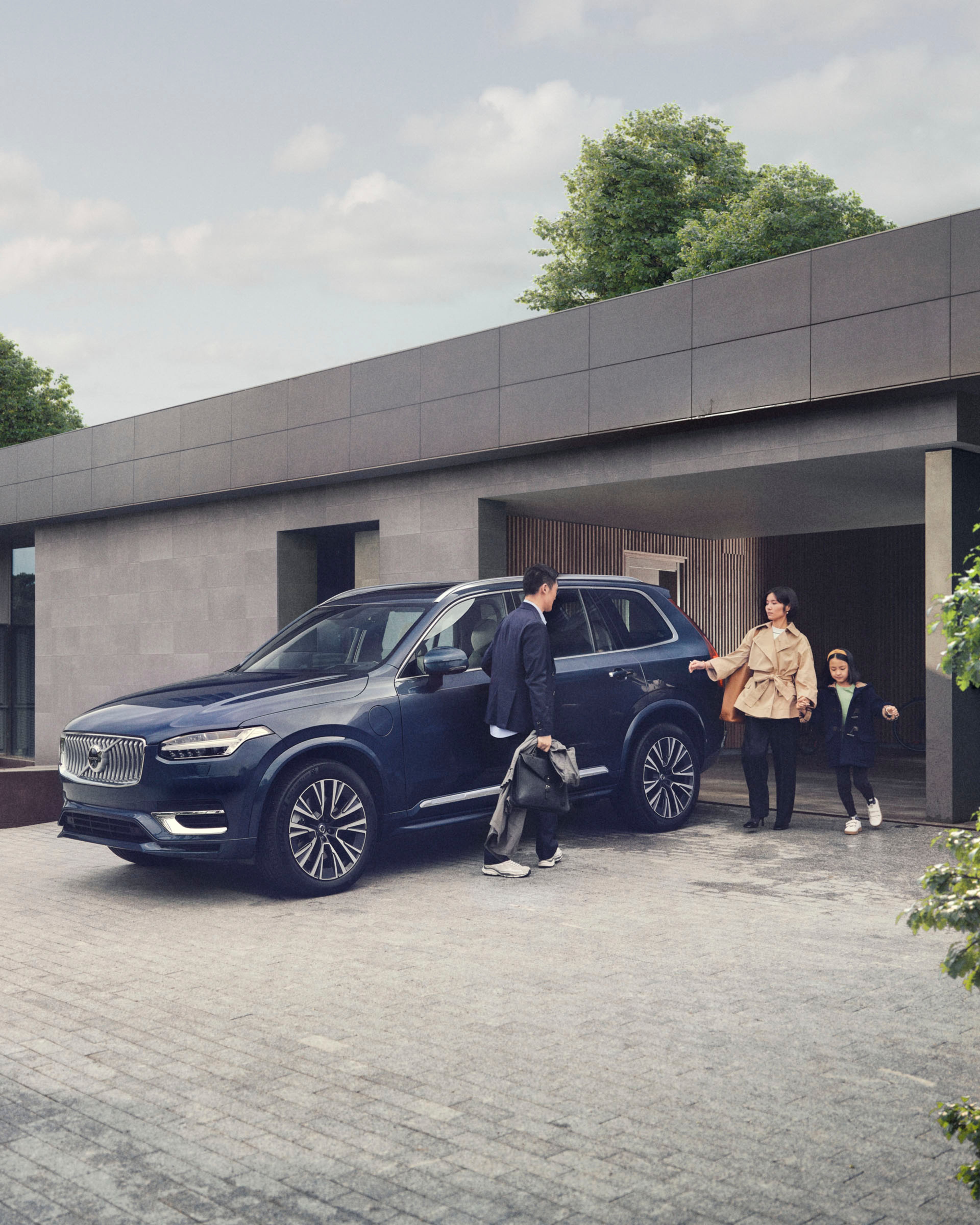 Volvo XC90 y una familia a la entrada del garaje de su casa