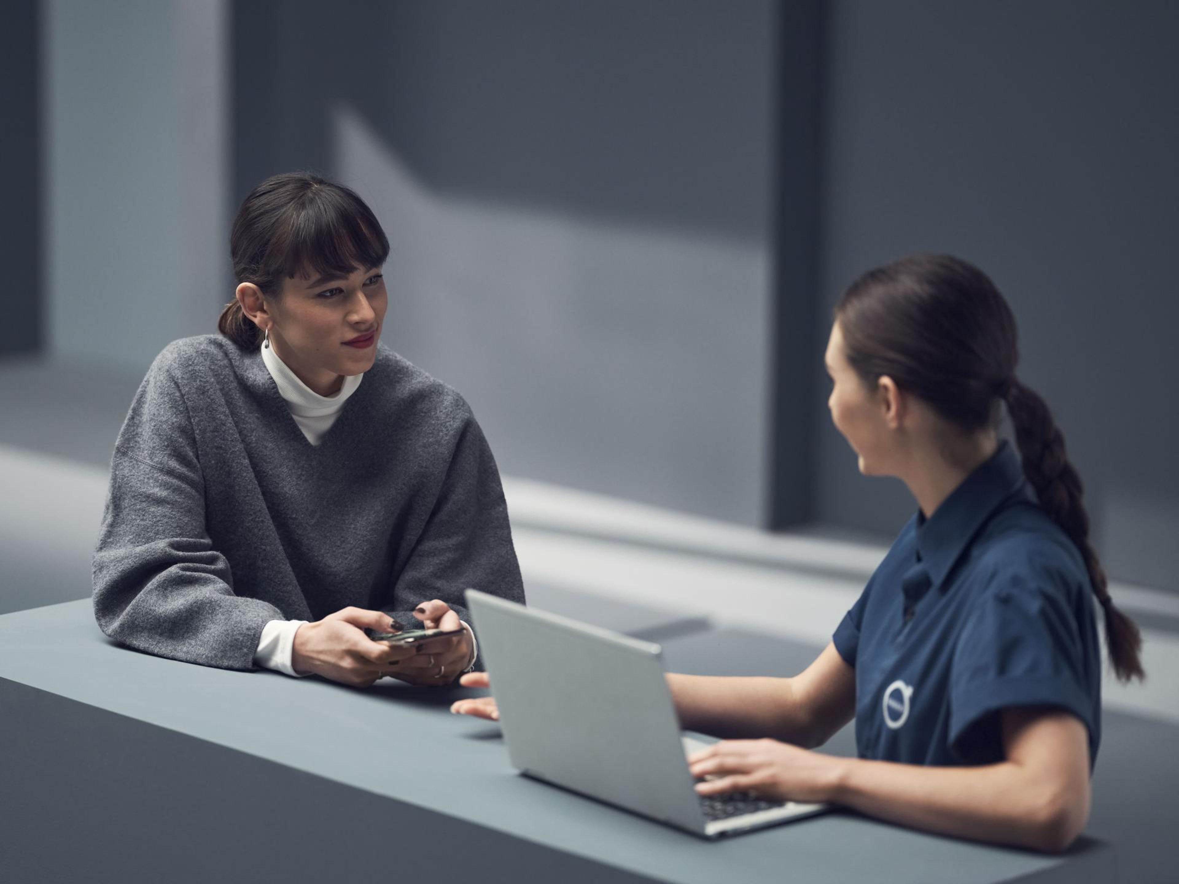 Mulher de cinzento a fazer uma marcação com uma funcionária volvo