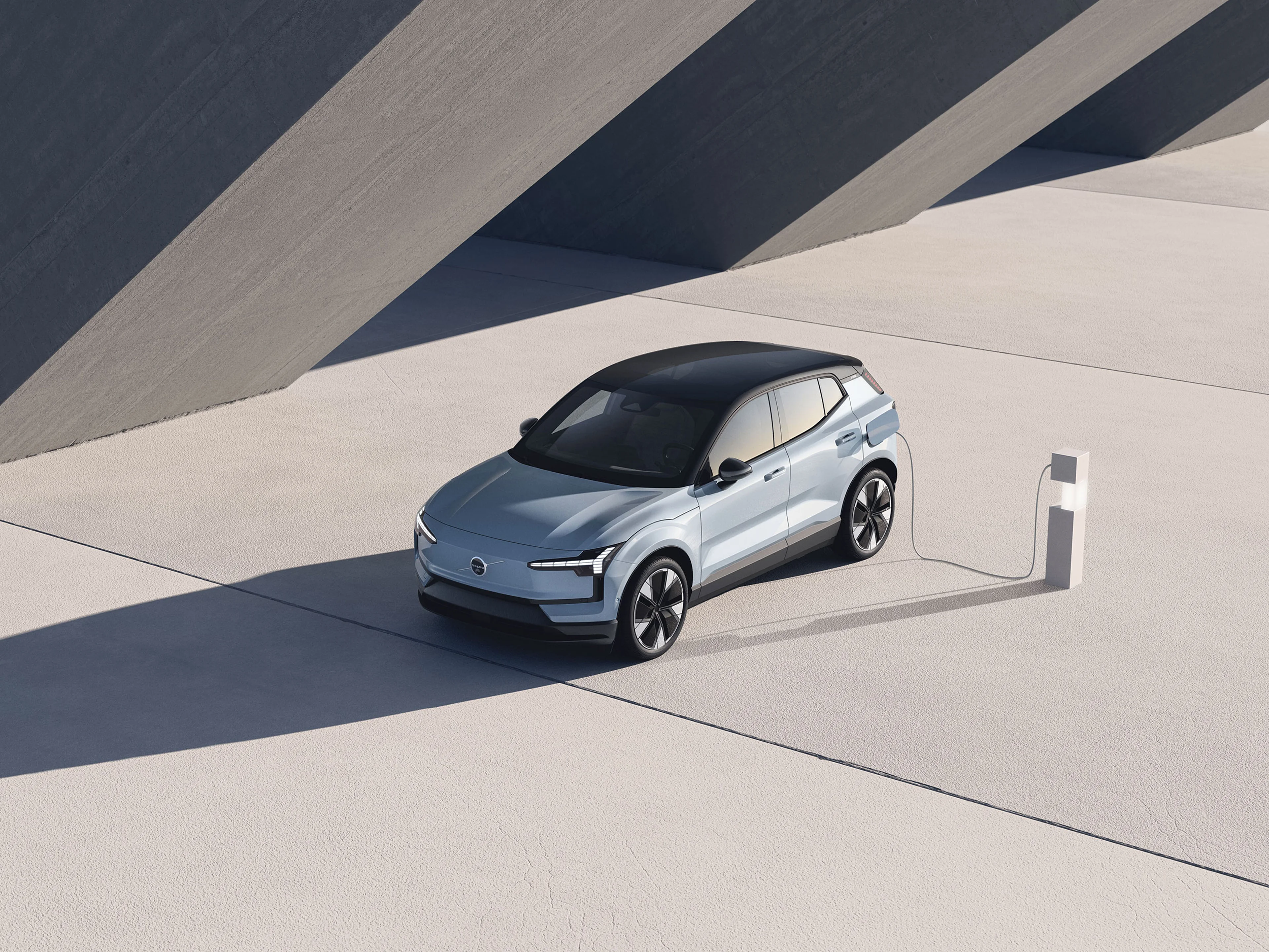 Volvo EX30 en charge à une borne moderne dans un cadre architectural minimaliste