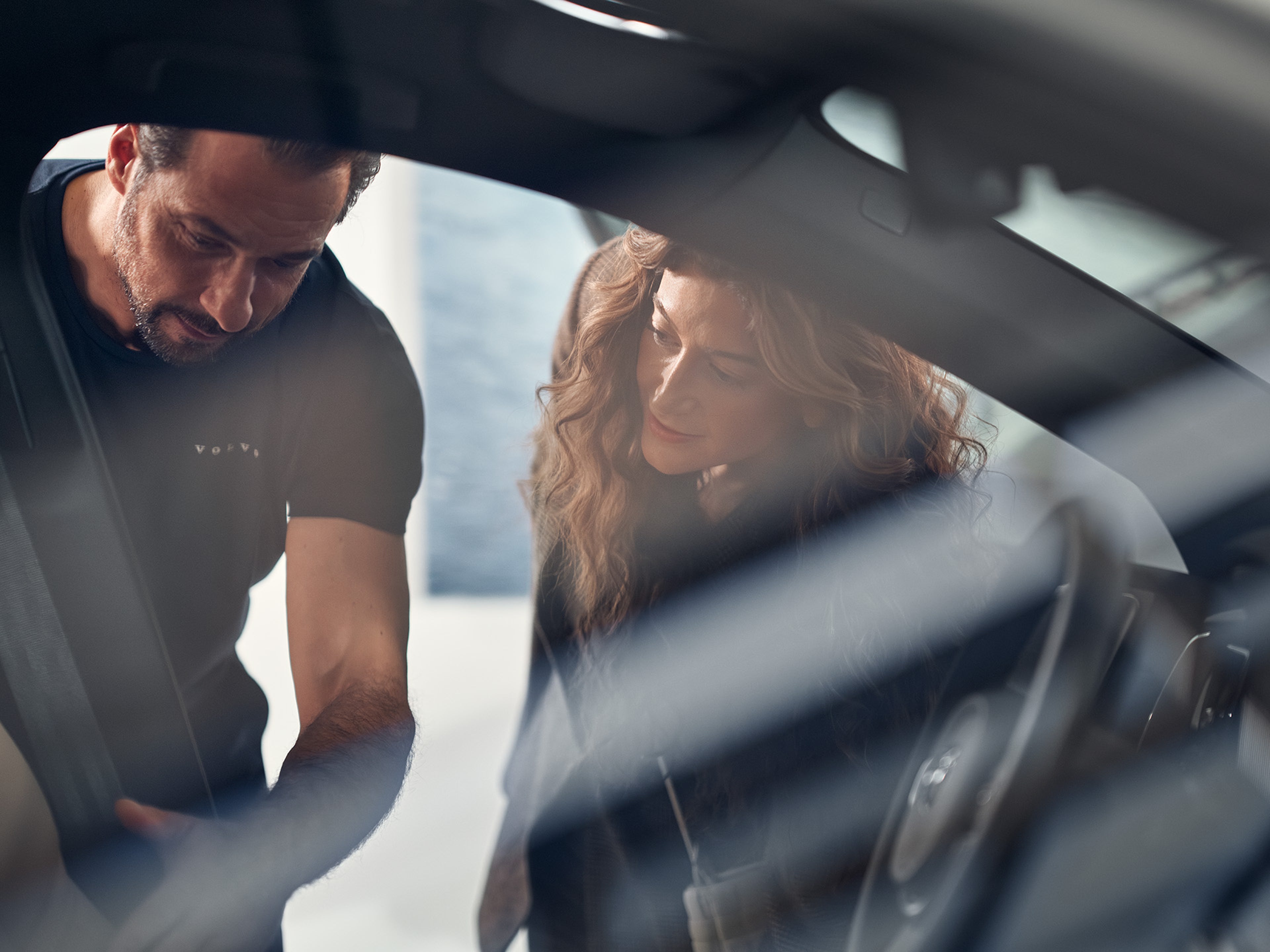 Funcinário da Volvo vestido de azul a dar infromações a uma mulher vestida de tons claros