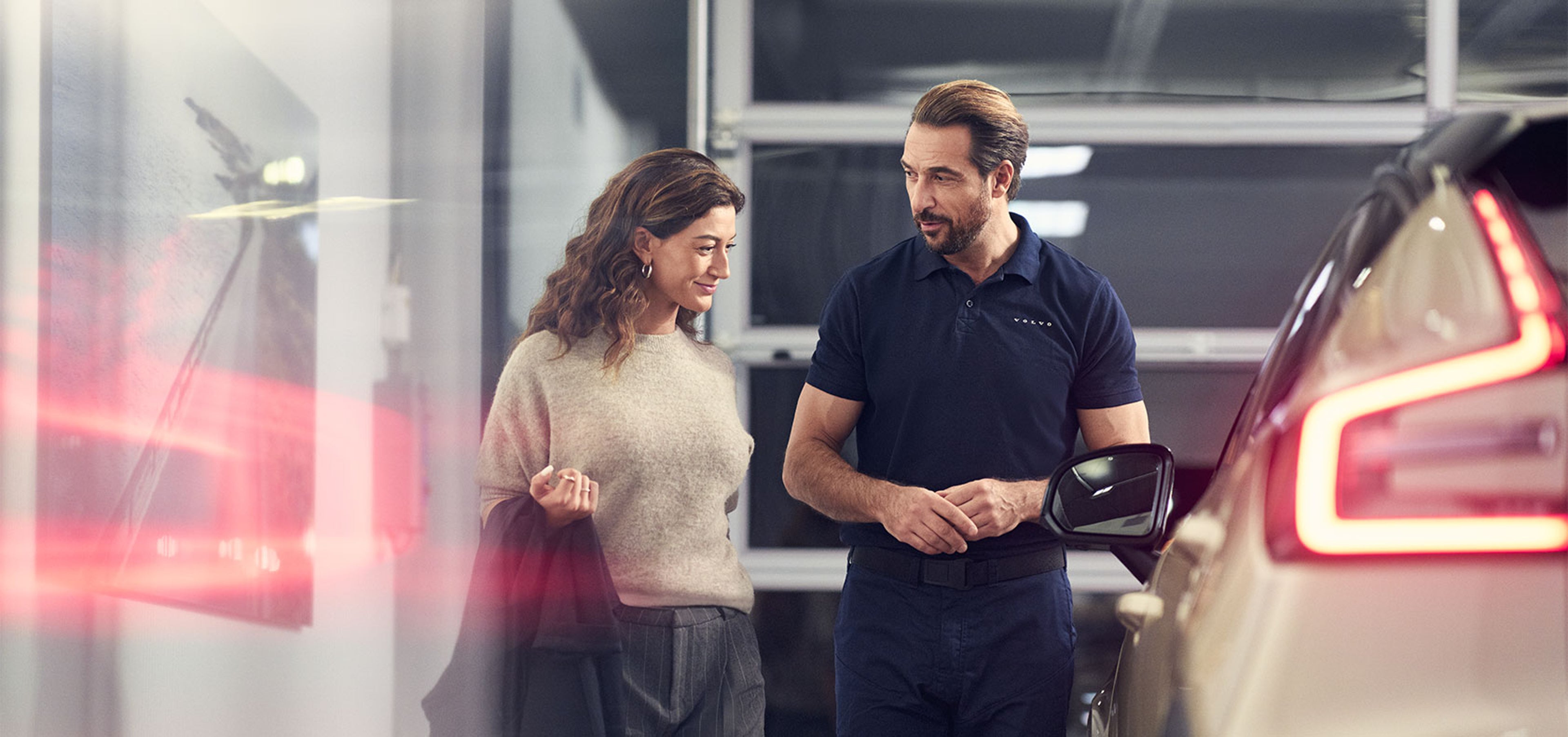 Dans un atelier Volvo, un technicien échange avec une cliente et lui présente le programme Les privilèges V+