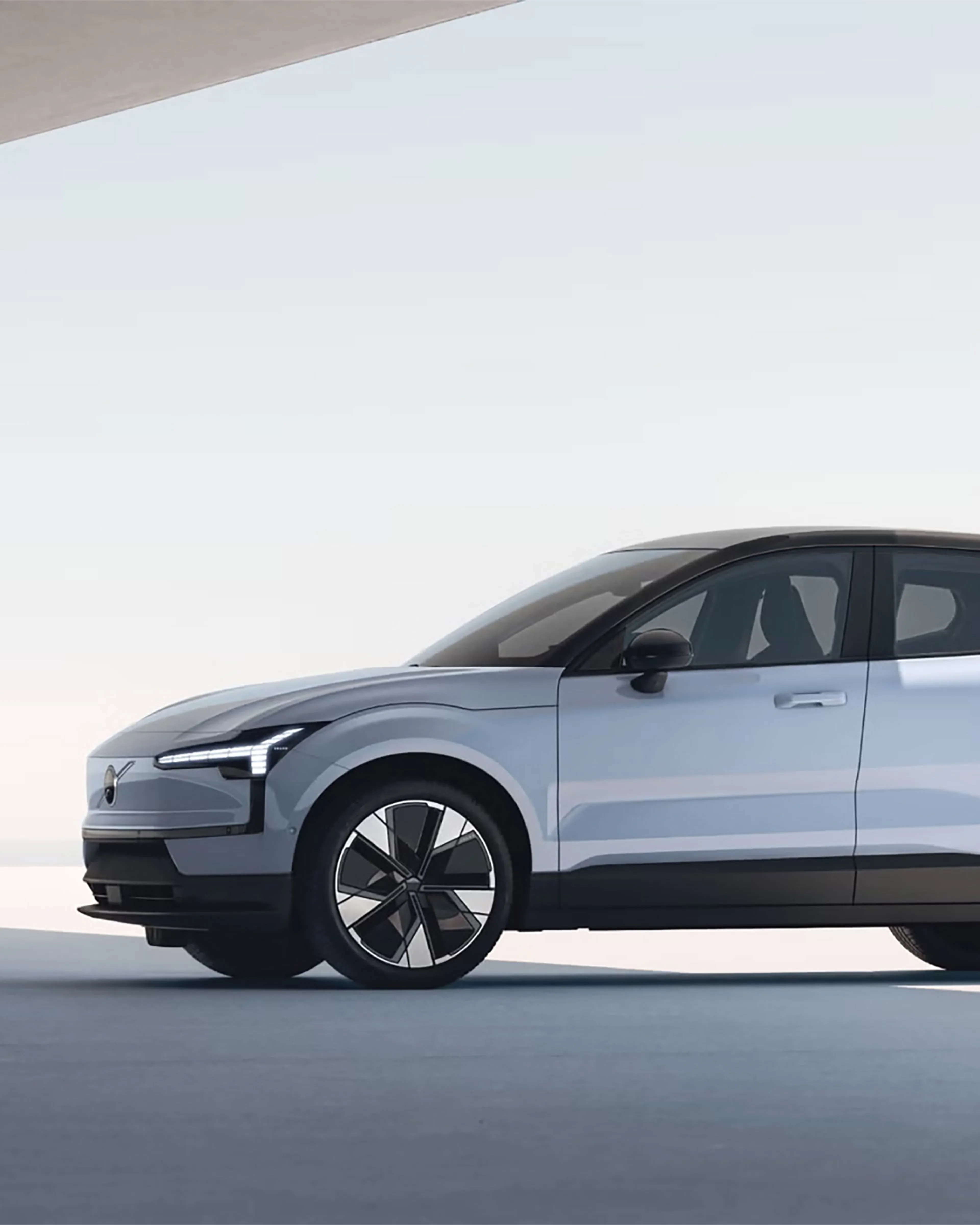 Vue latérale d’une Volvo EX30 blanche moderne avec toit noir et grandes roues, dans un décor minimaliste