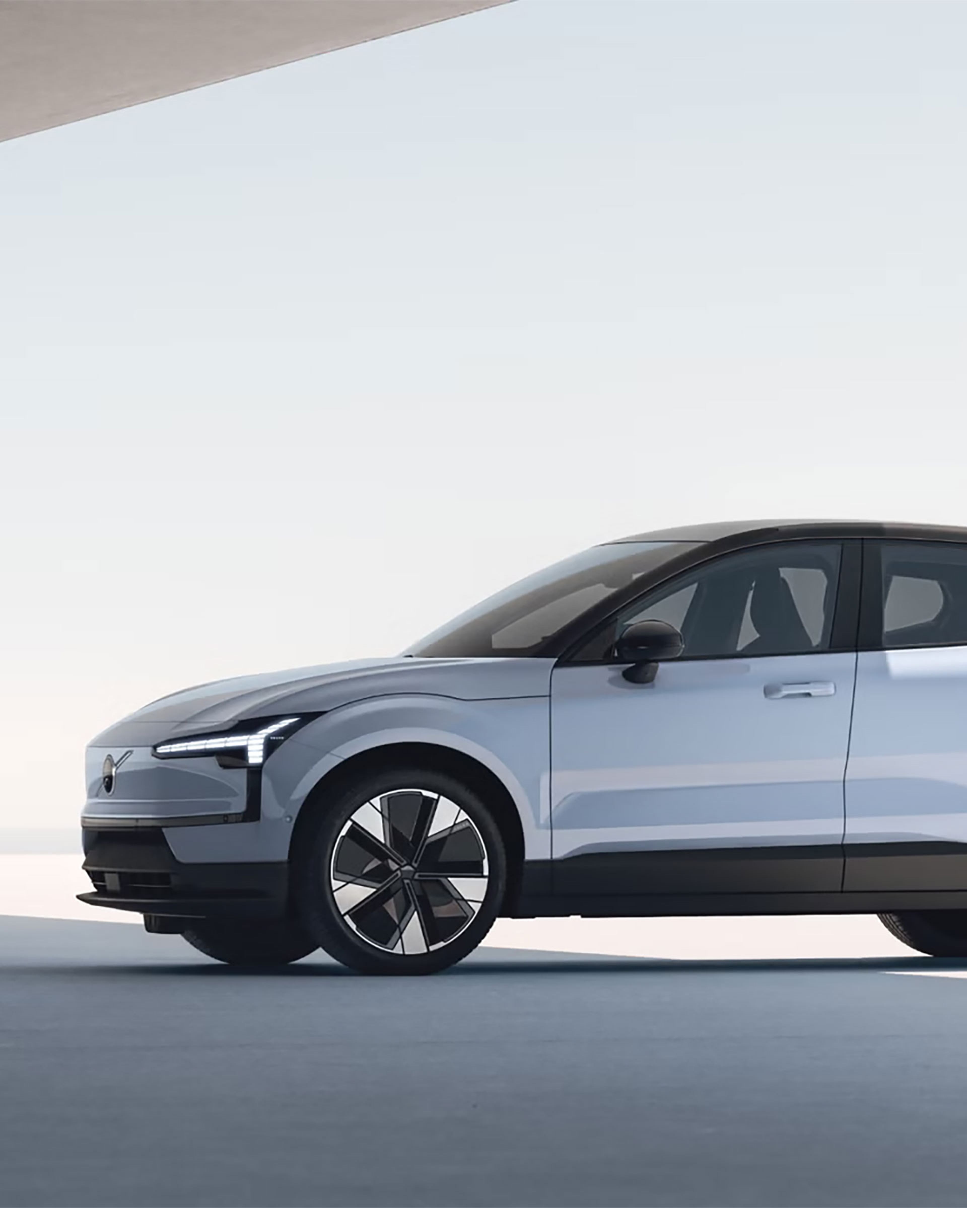 Vue latérale d’une Volvo EX30 blanche moderne avec toit noir et grandes roues, dans un décor minimaliste