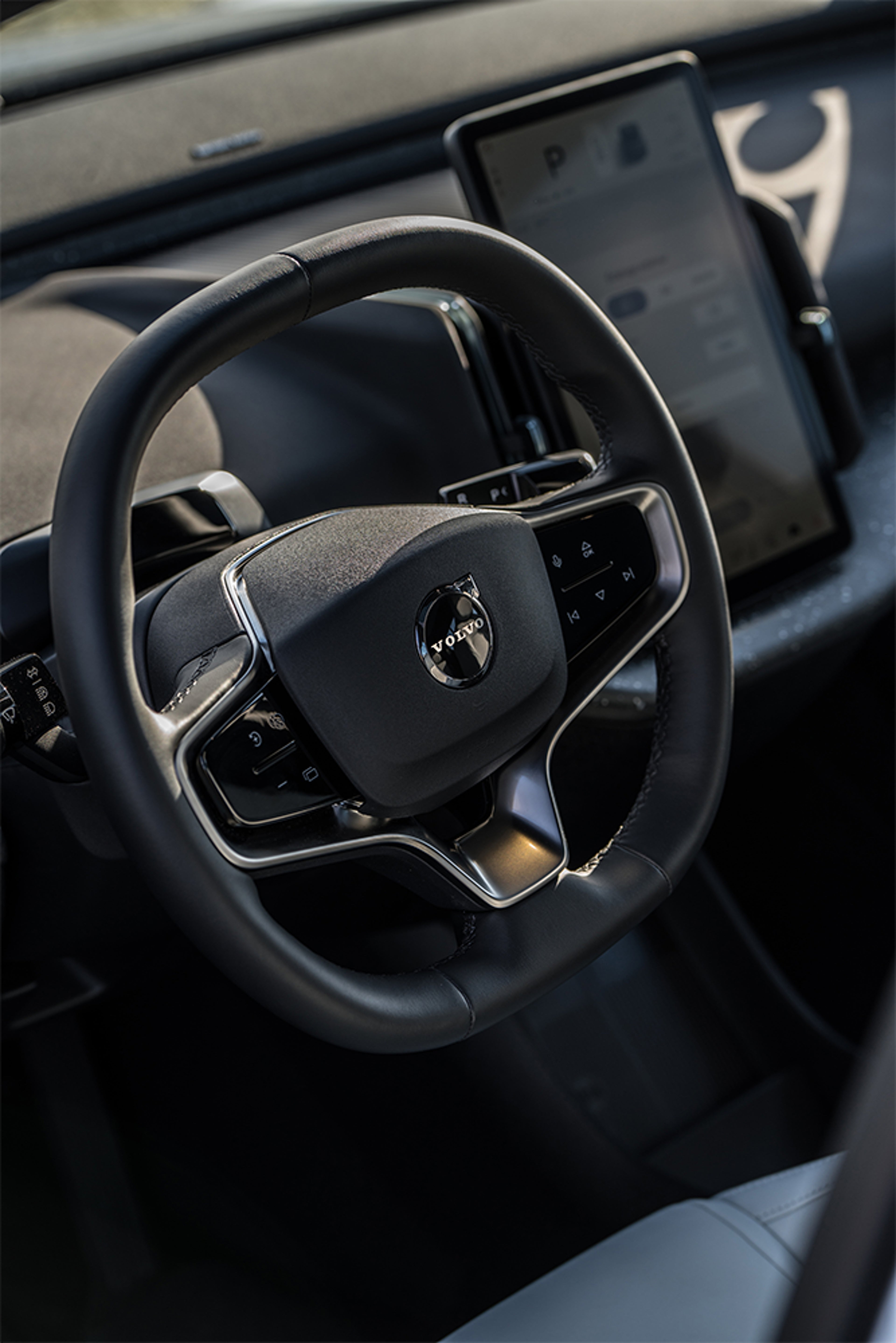 Volant de voiture avec écran tactile affichant infos de stationnement, intérieur moderne et épuré.