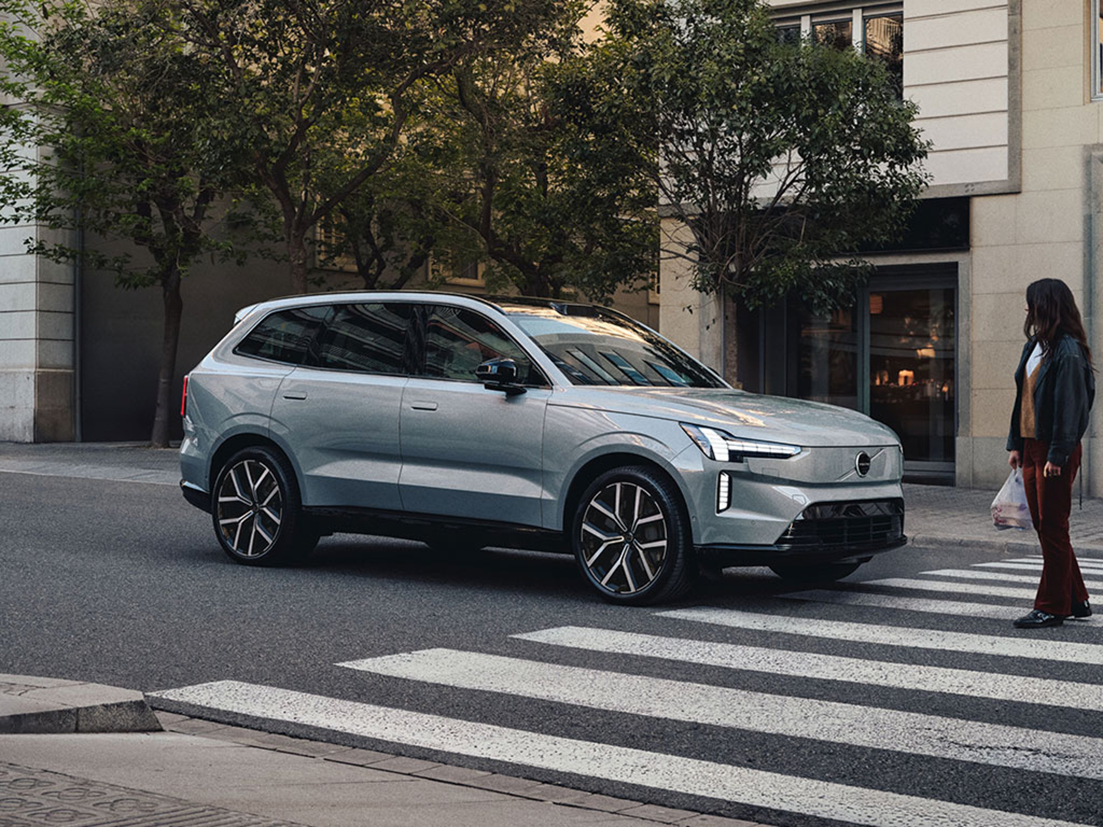 EX90 à l'arrêt après un freinage d'urgence devant un passage piéton avec un femme le traversant