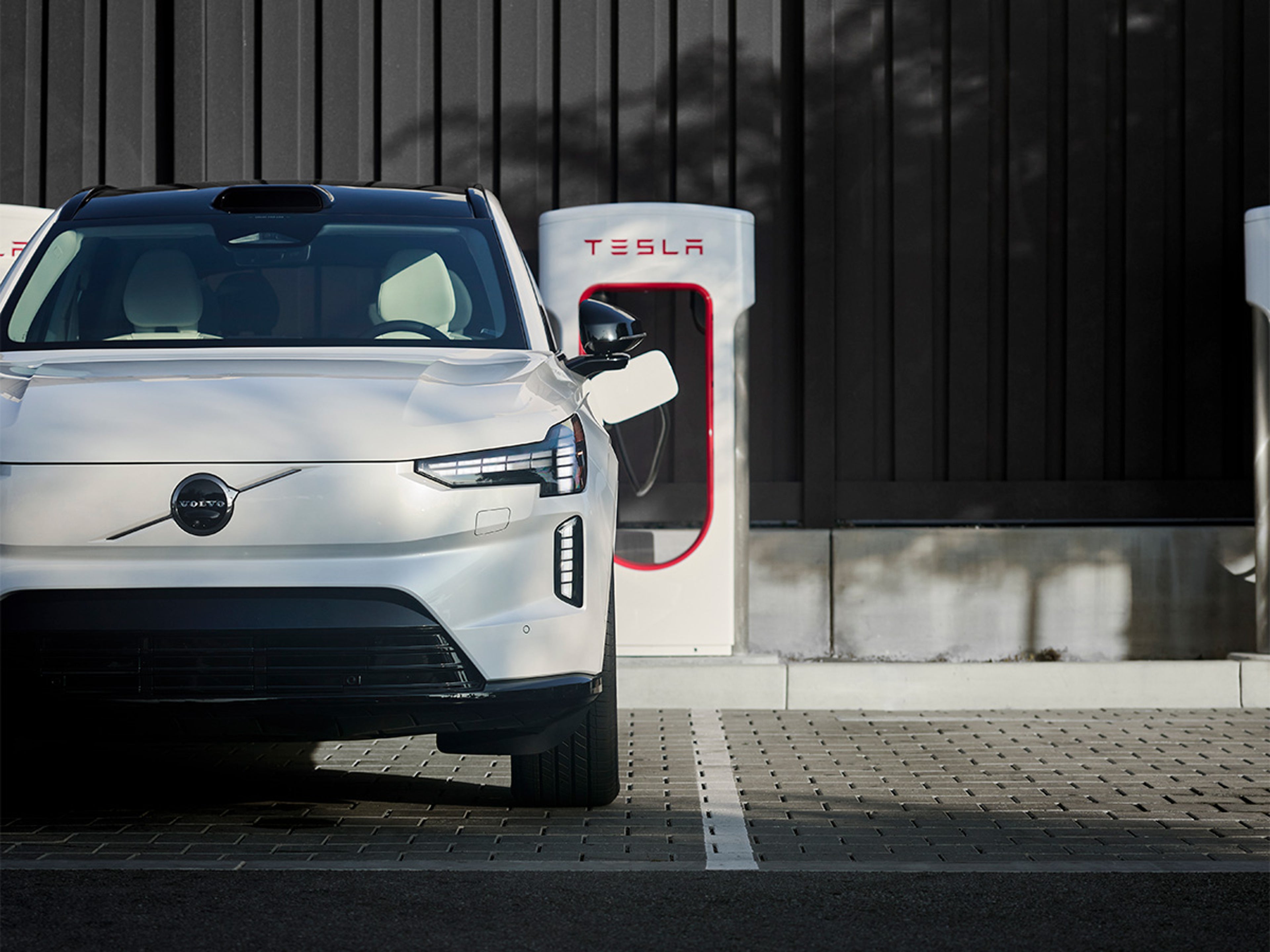 EX90 charging at a Tesla Supercharger