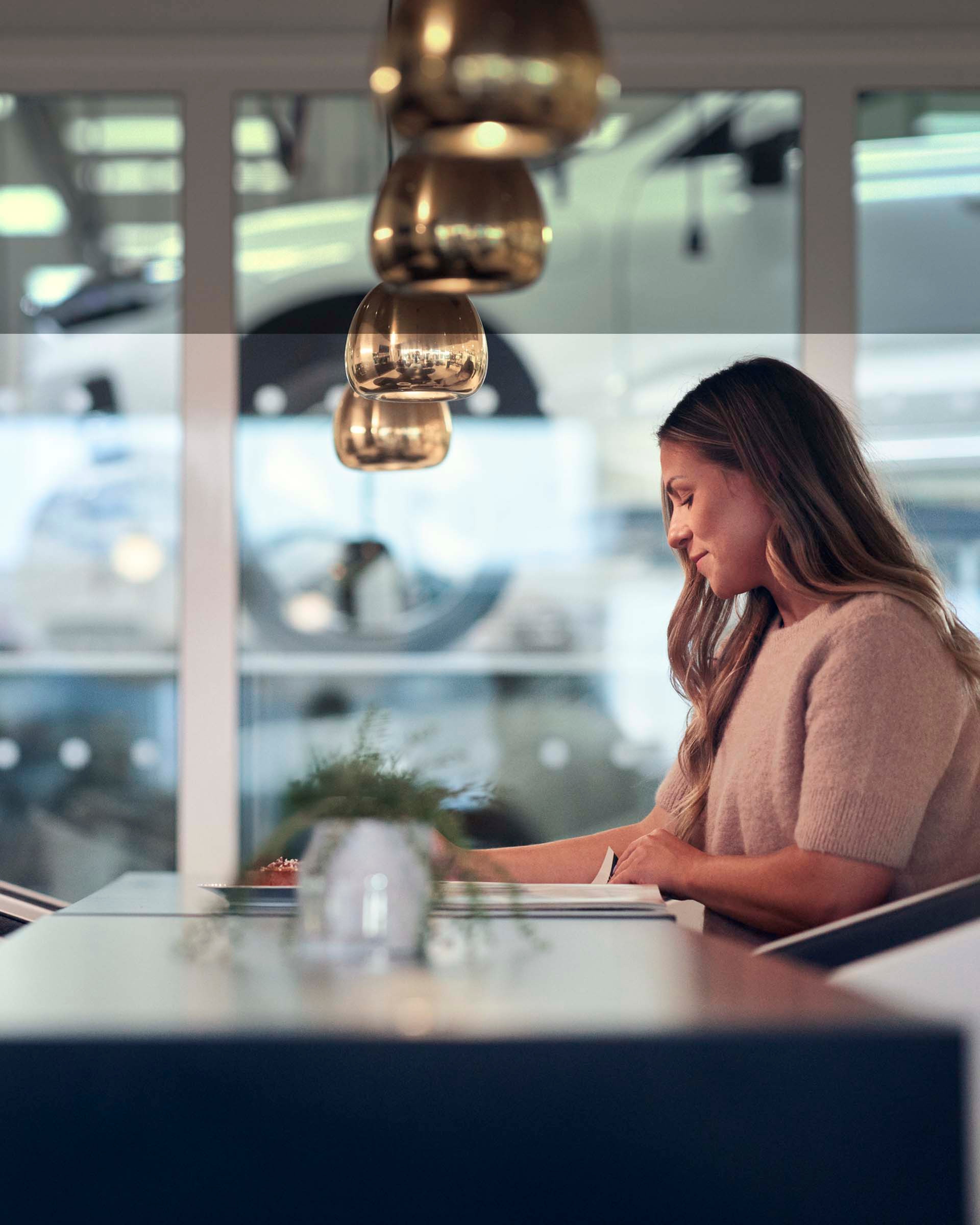 Una mujer leyendo en una sala de espera de un servicio oficial Volvo mientras su vehículo pasa el mantenimiento
