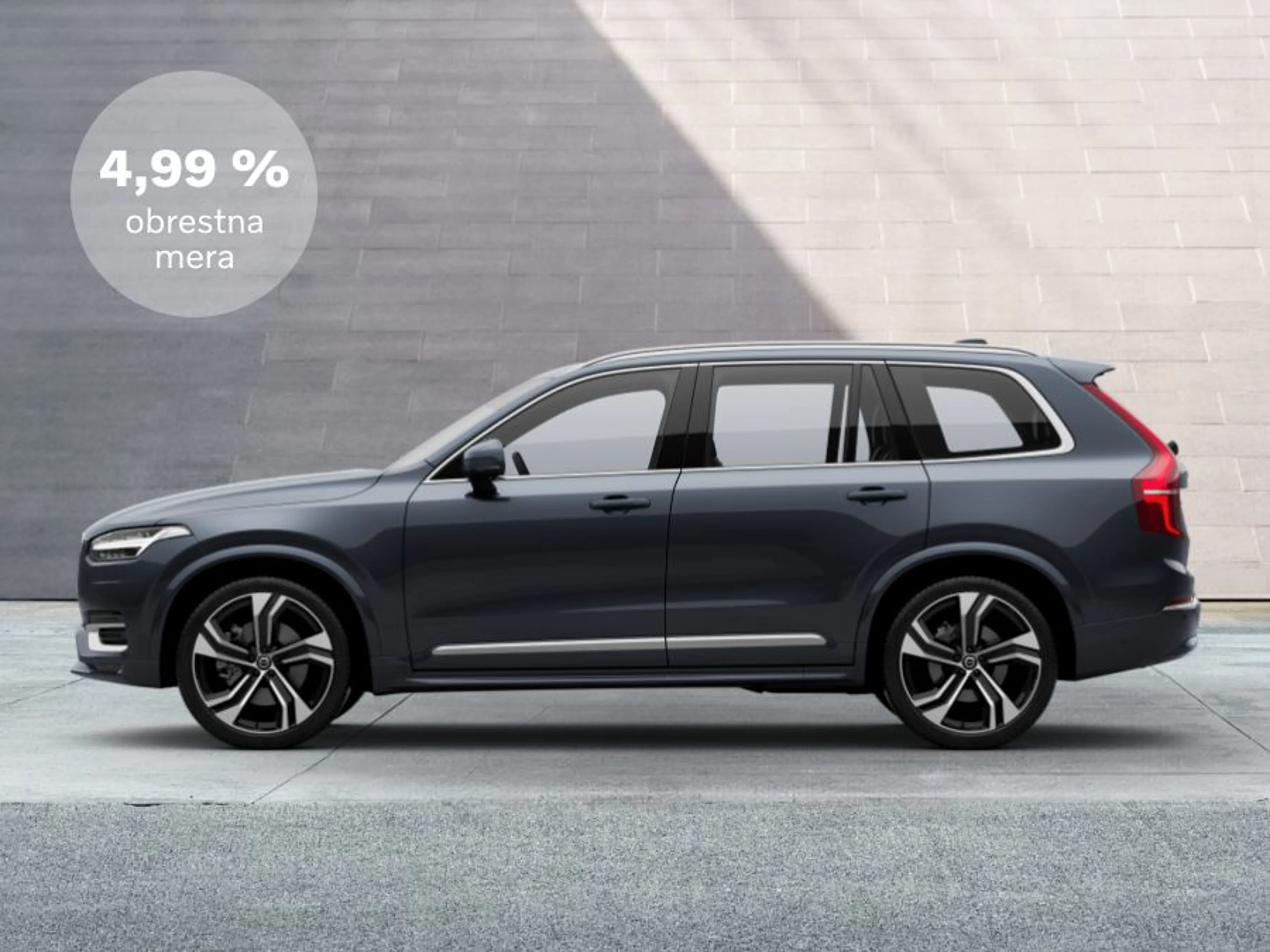 Volvo XC90 parkiran pred sivo steno, stranski pogled.