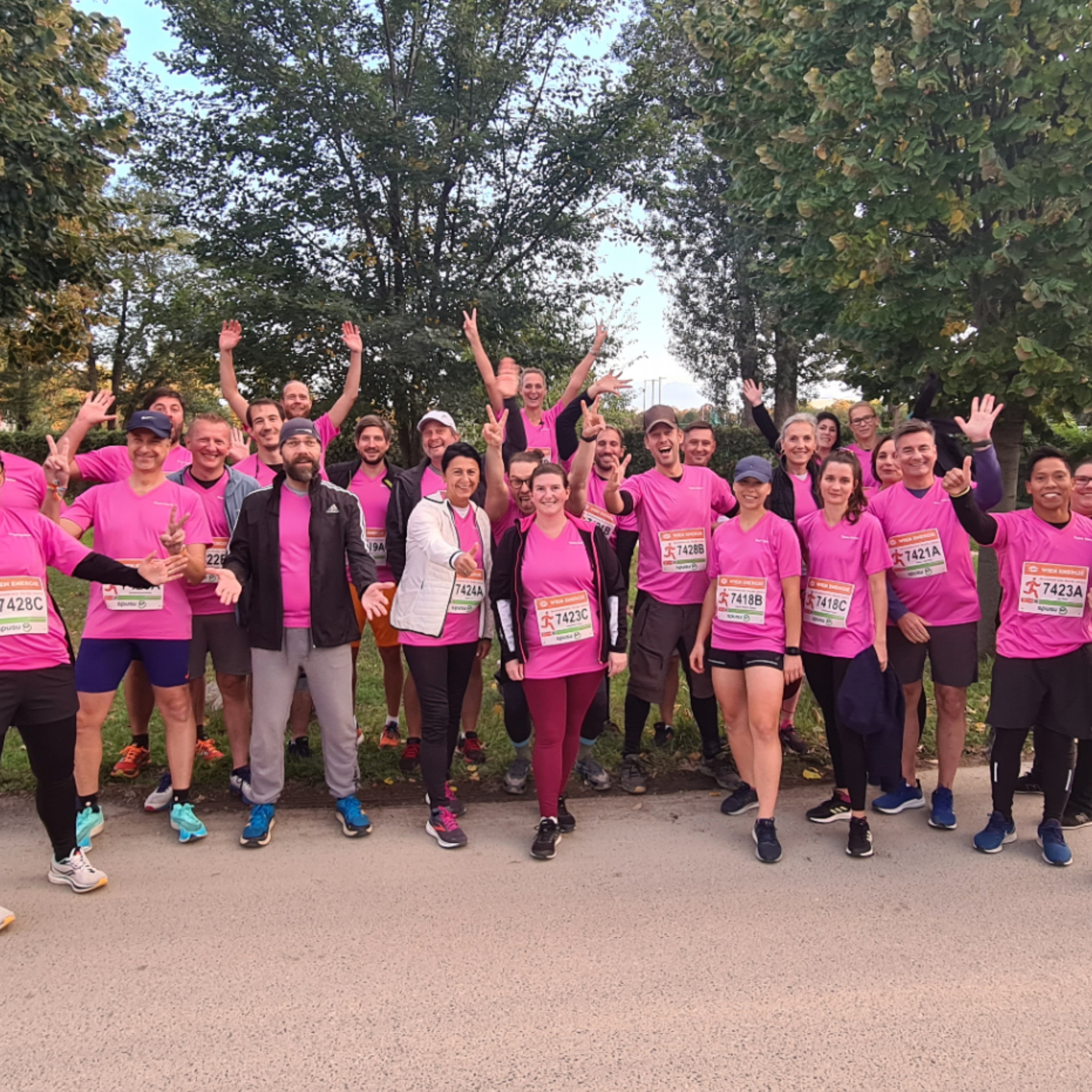 25 Personen aus dem Volvo Car Austria Team sind in pinken Laufshirts versammelt und machen ein Foto mit lustigen Posen