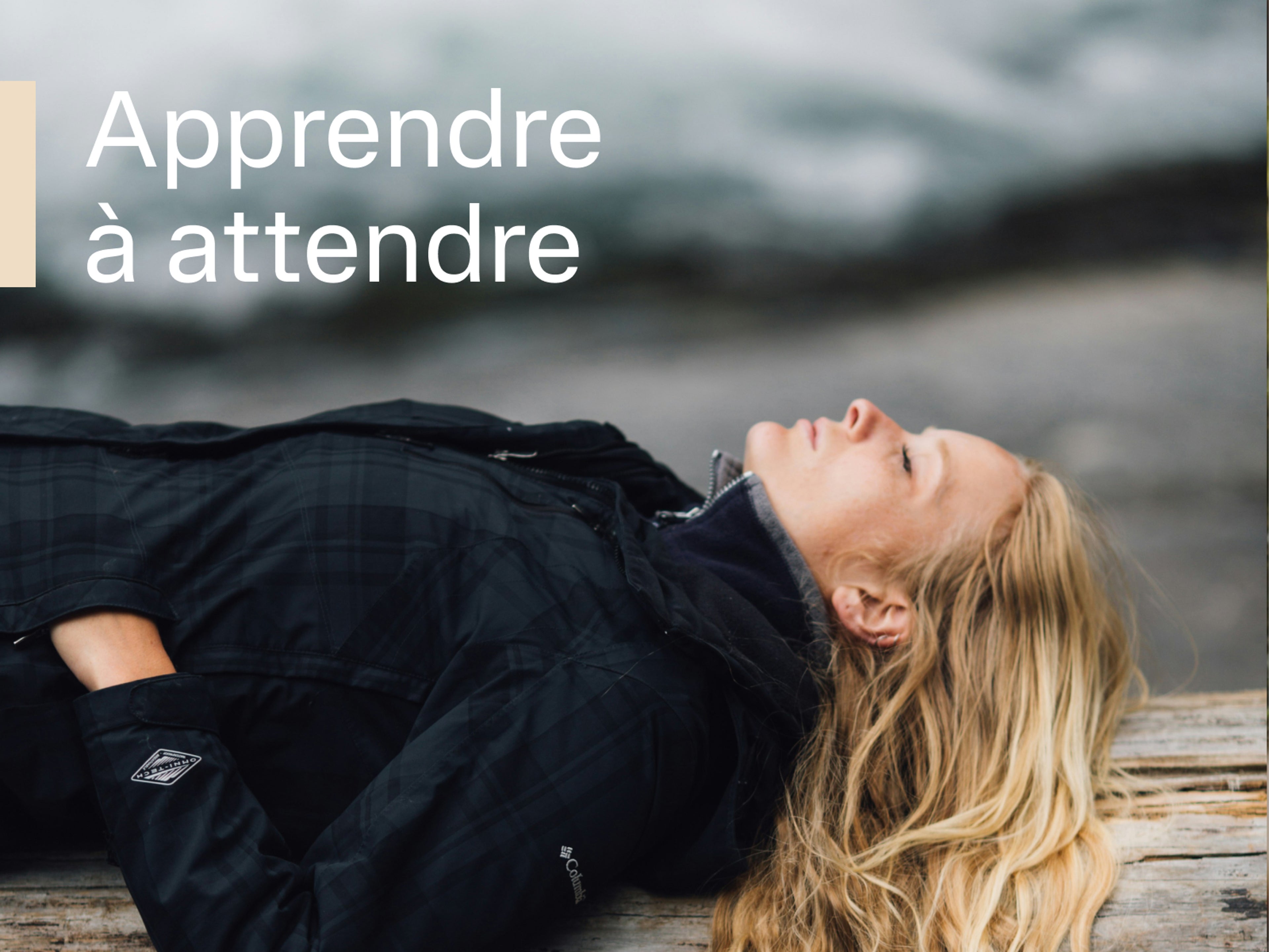 Une femme est allongée paisiblement sur une bûche près d'une rivière, avec un texte blanc au premier plan : Apprendre à attendre.