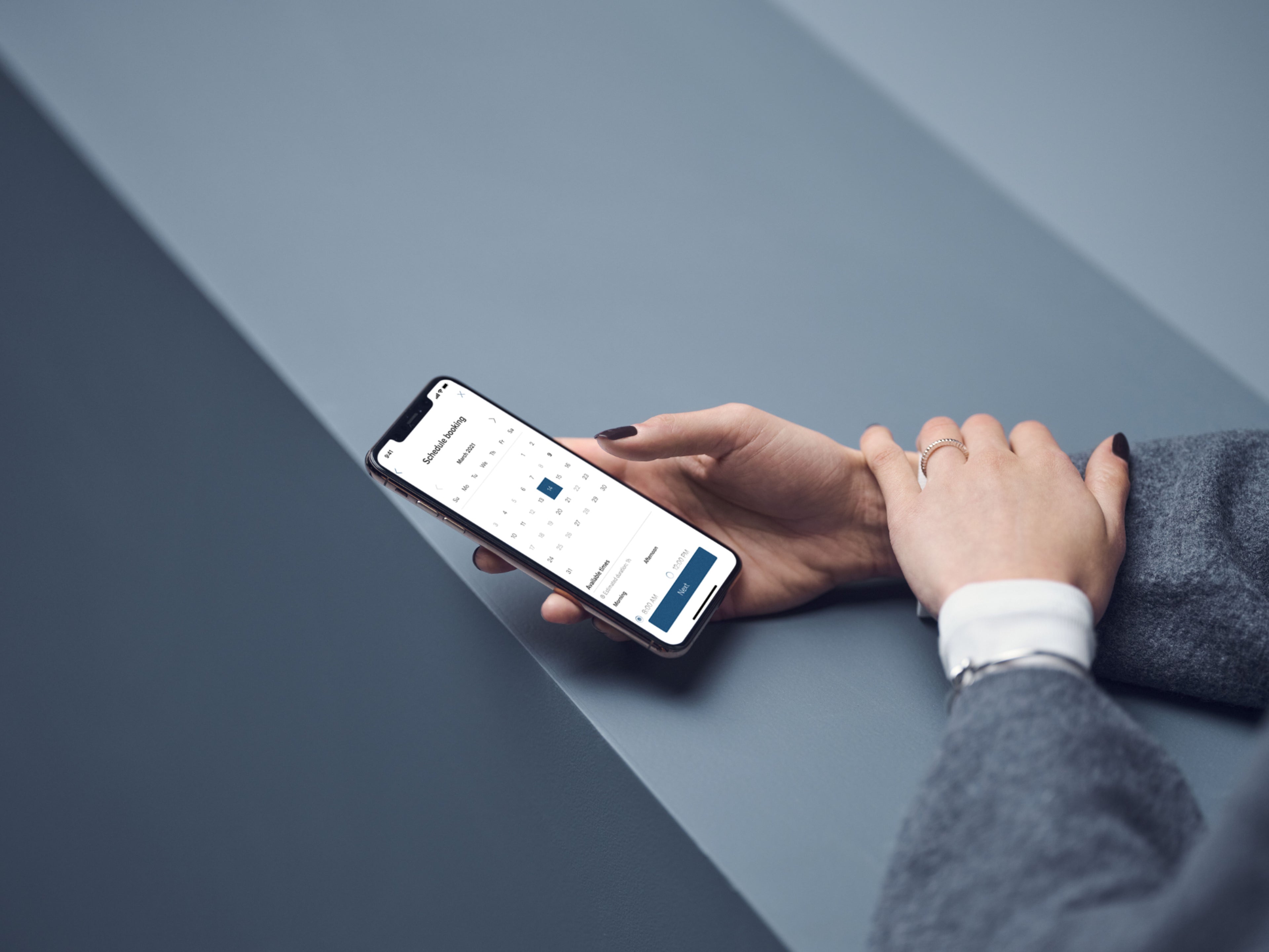 Ein Smartphone liegt auf einer blauen Oberfläche. Darauf sieht man eine Bildschirmoberfläche zum buchen eines Servicetermins.