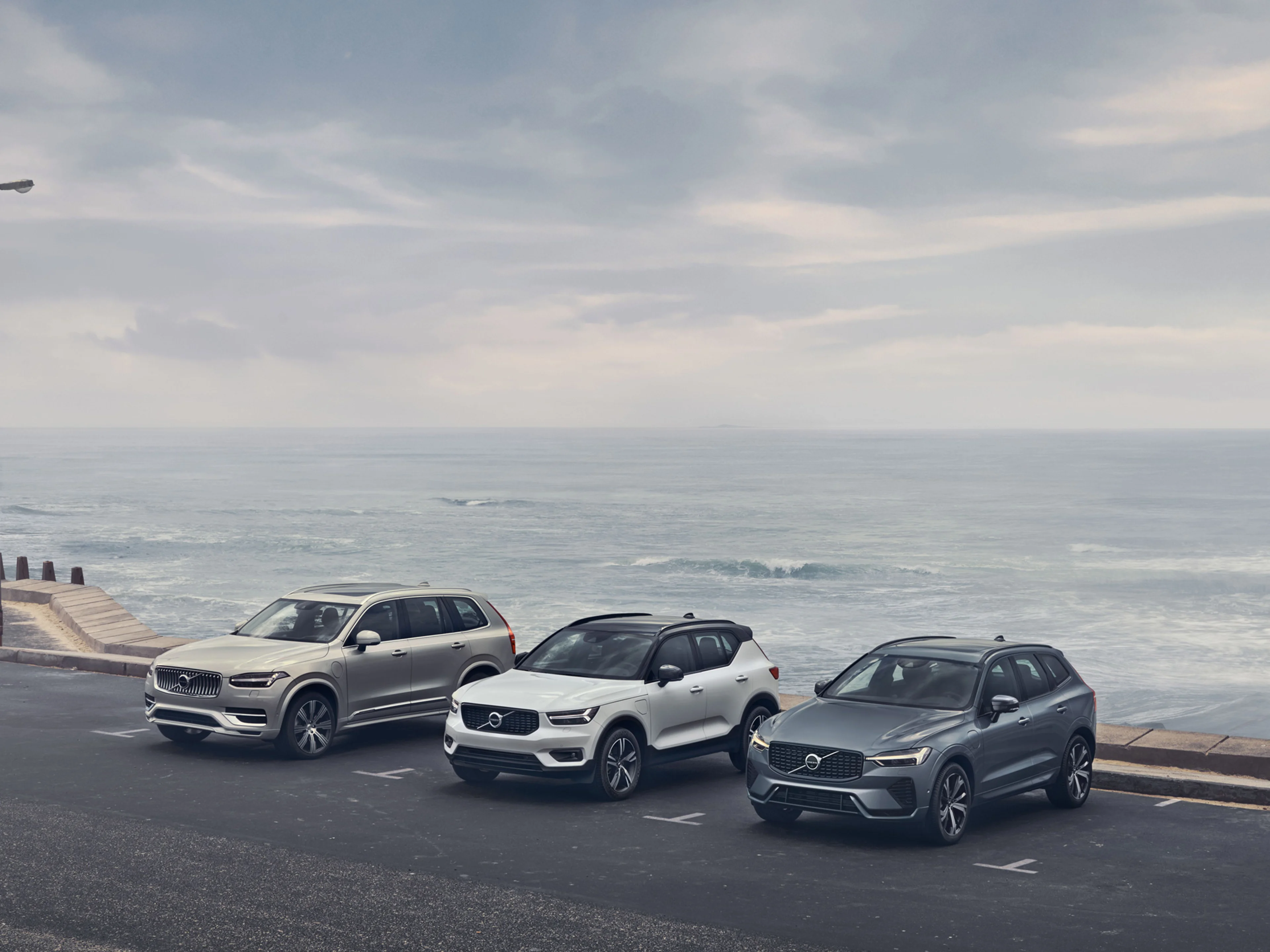 Gama XC de vehículos Volvo estacionados a la orilla del mar.