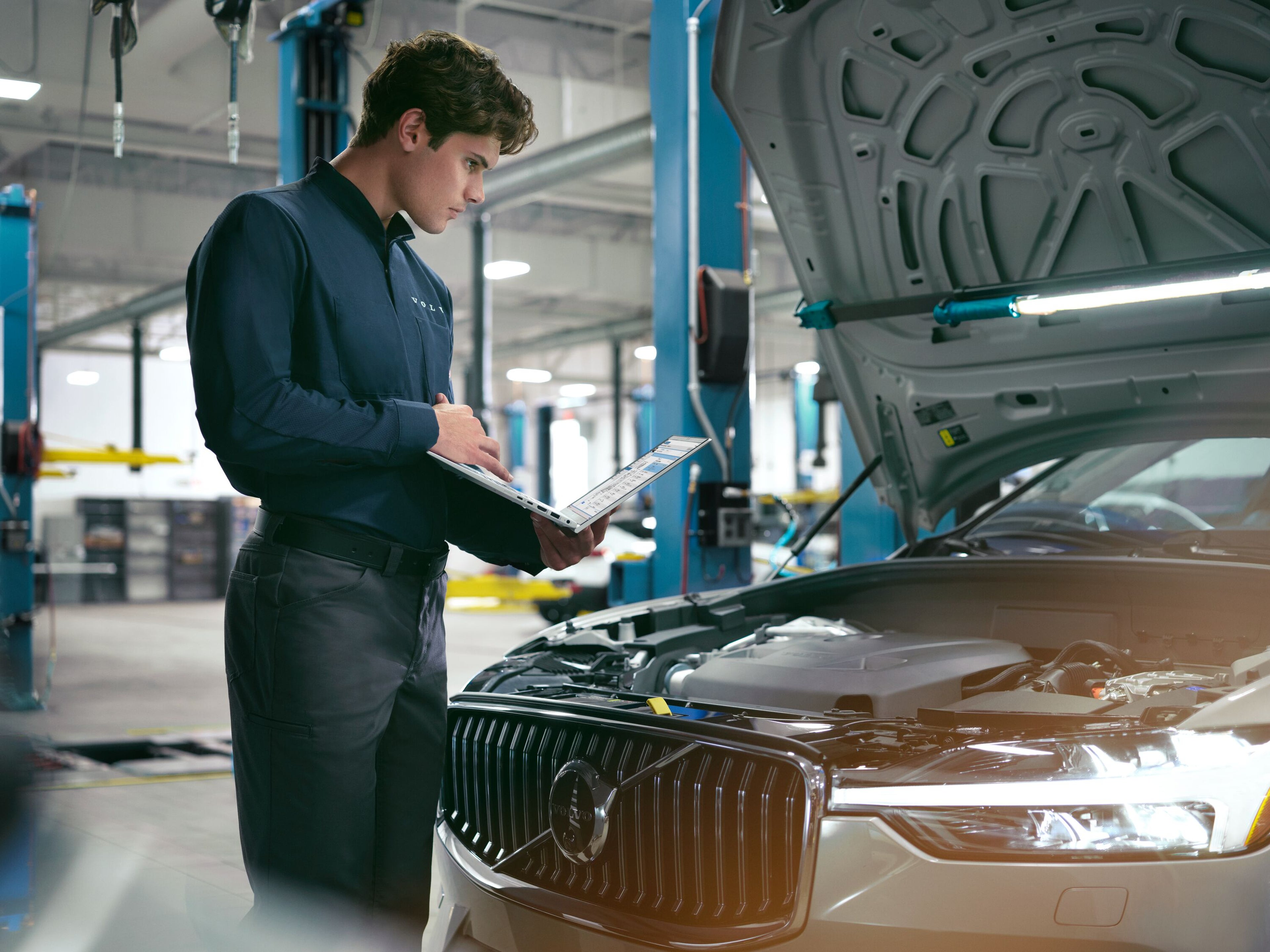 Technician working on Volvo XC60 with hood open