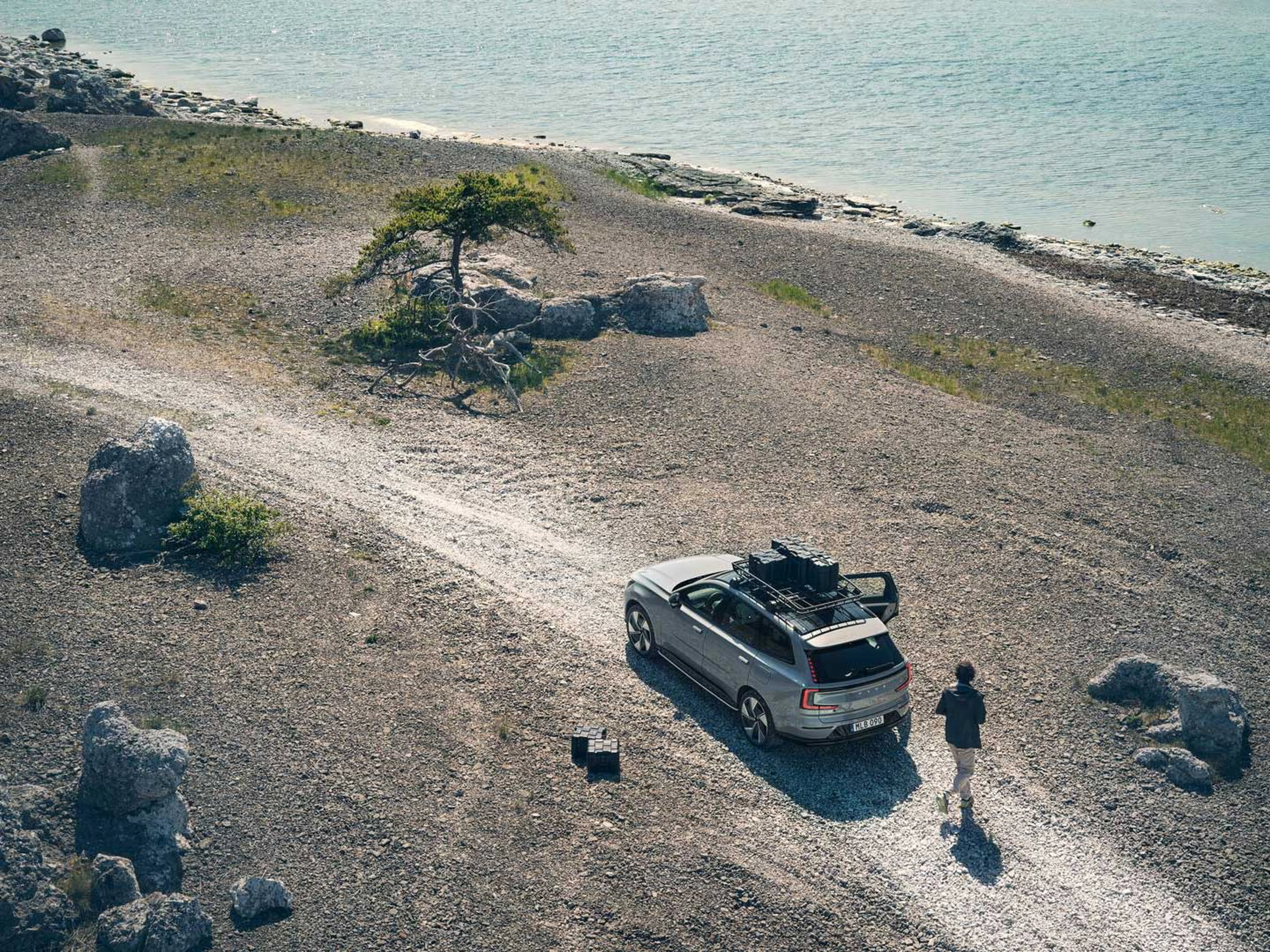En stor elbil fra Volvo holder på en grusvej ved vandet set bagfra i fugleperspektiv.