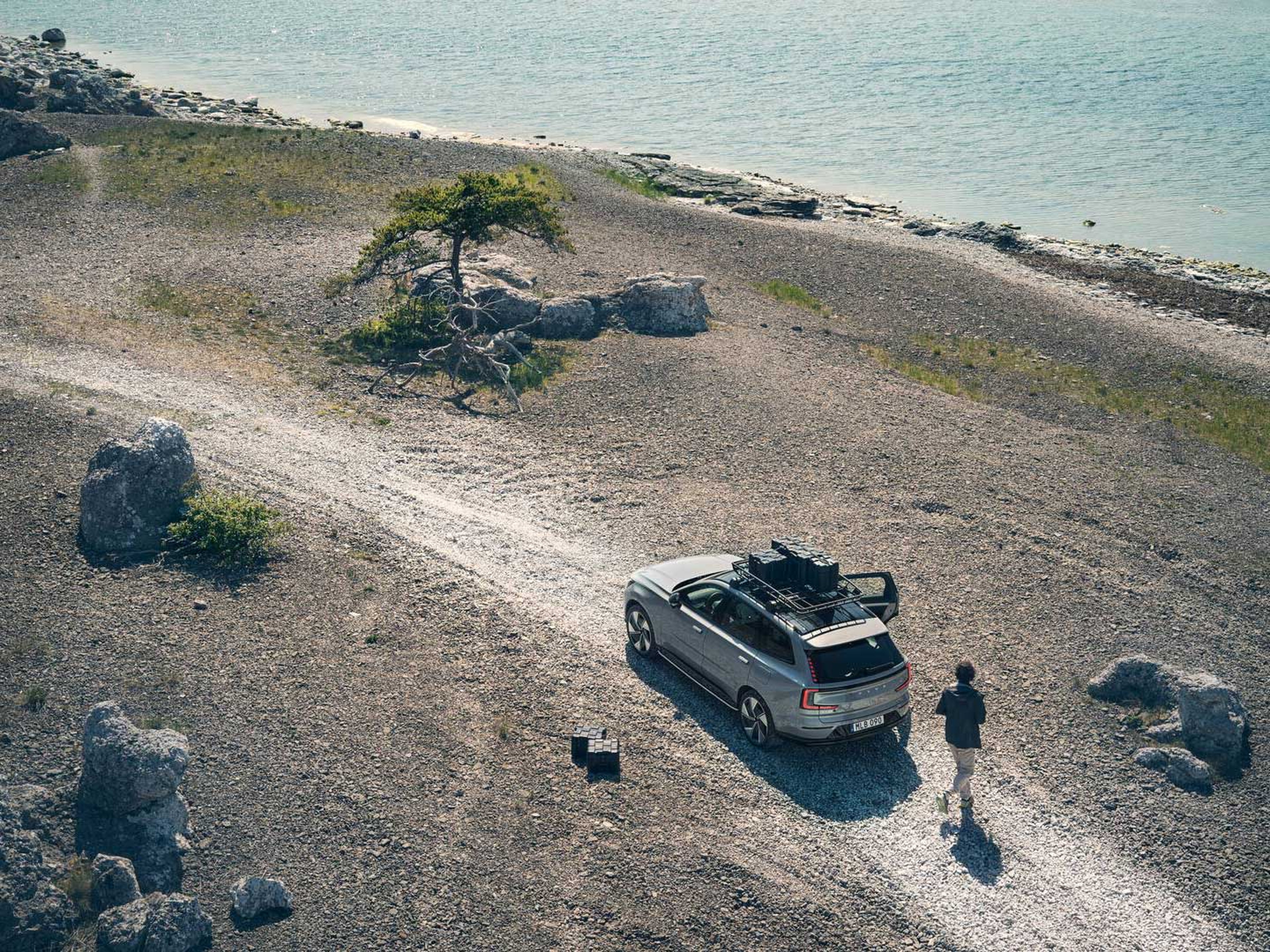 En stor elbil fra Volvo holder på en grusvej ved vandet set bagfra i fugleperspektiv.