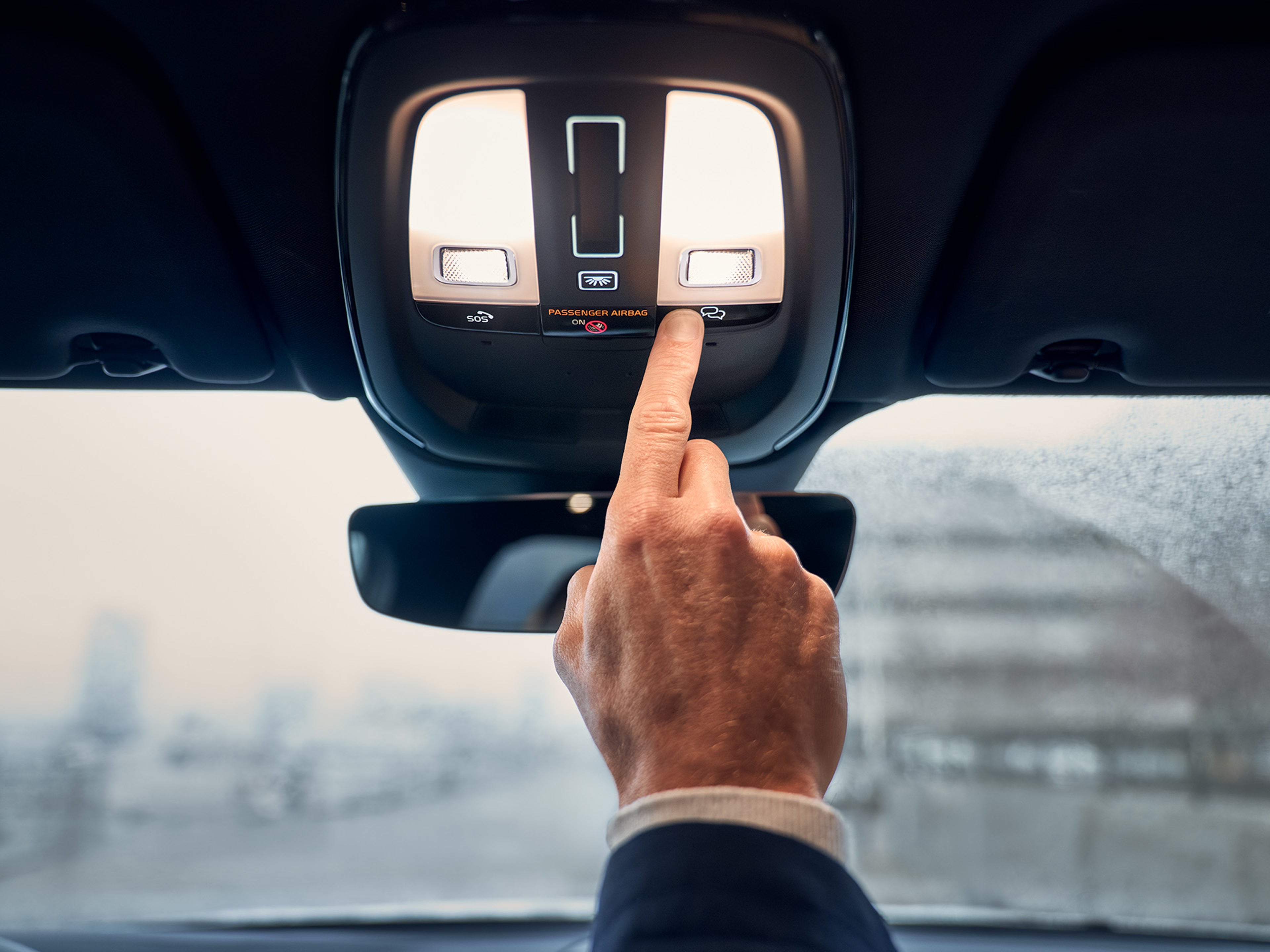 Close da mão de uma pessoa a ligar as luzes de teto dentro de um Volvo