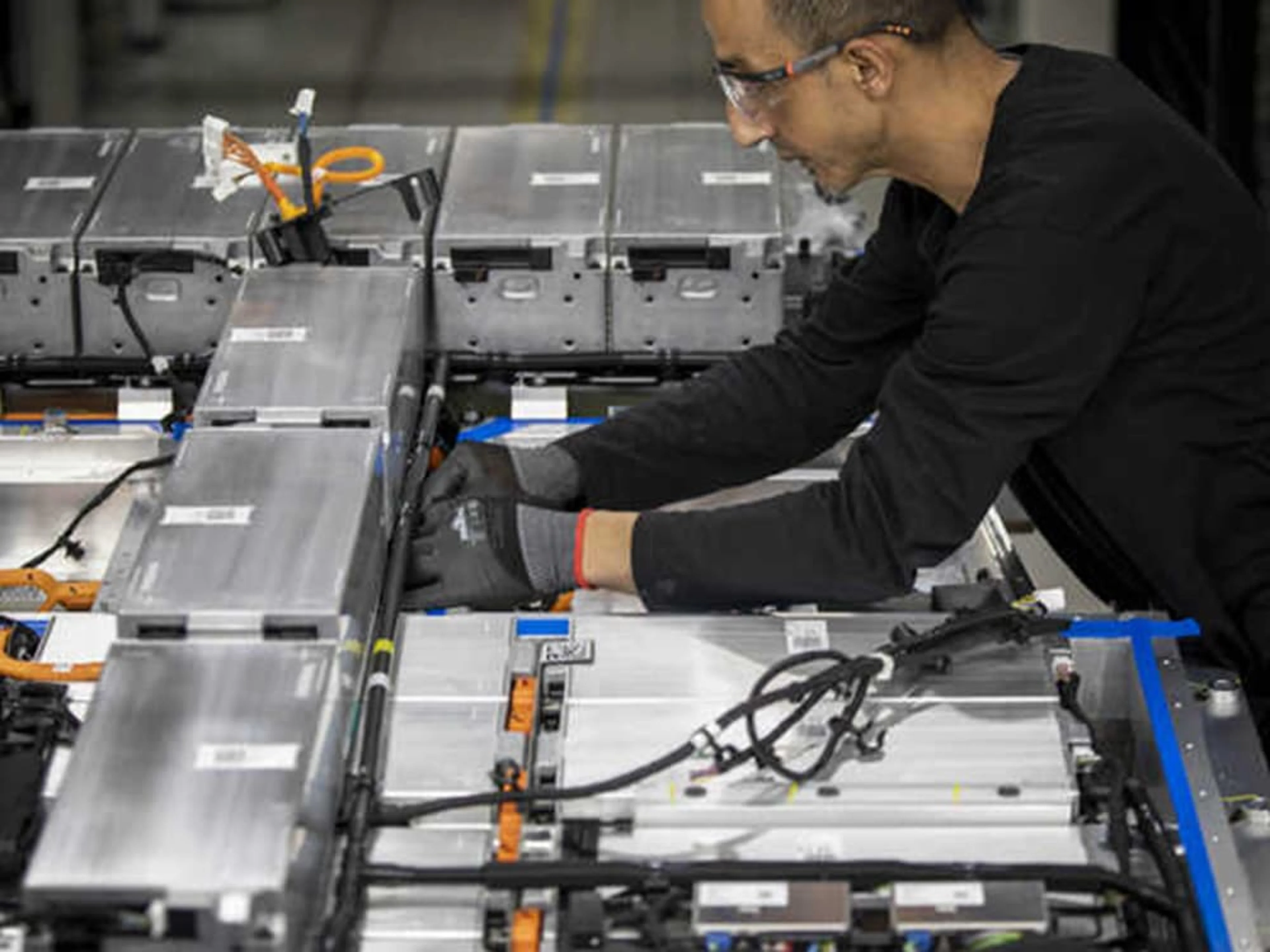 Un homme portant des lunettes de sécurité et des gants travaille sur une batterie dans l'usine Volvo Car de Gand.
