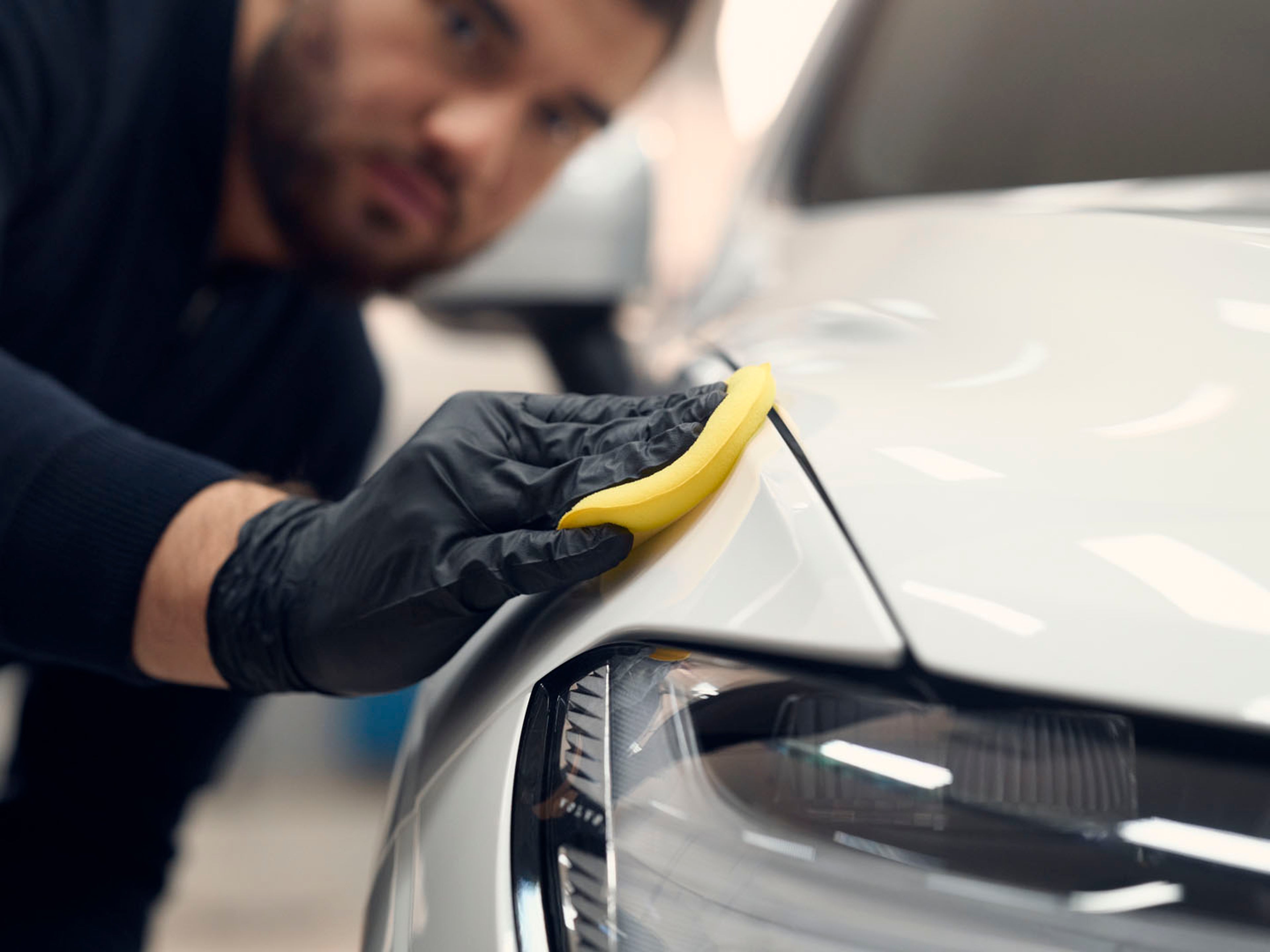 Un mecánico pasando una gamuza por la chapa de un vehículo Volvo