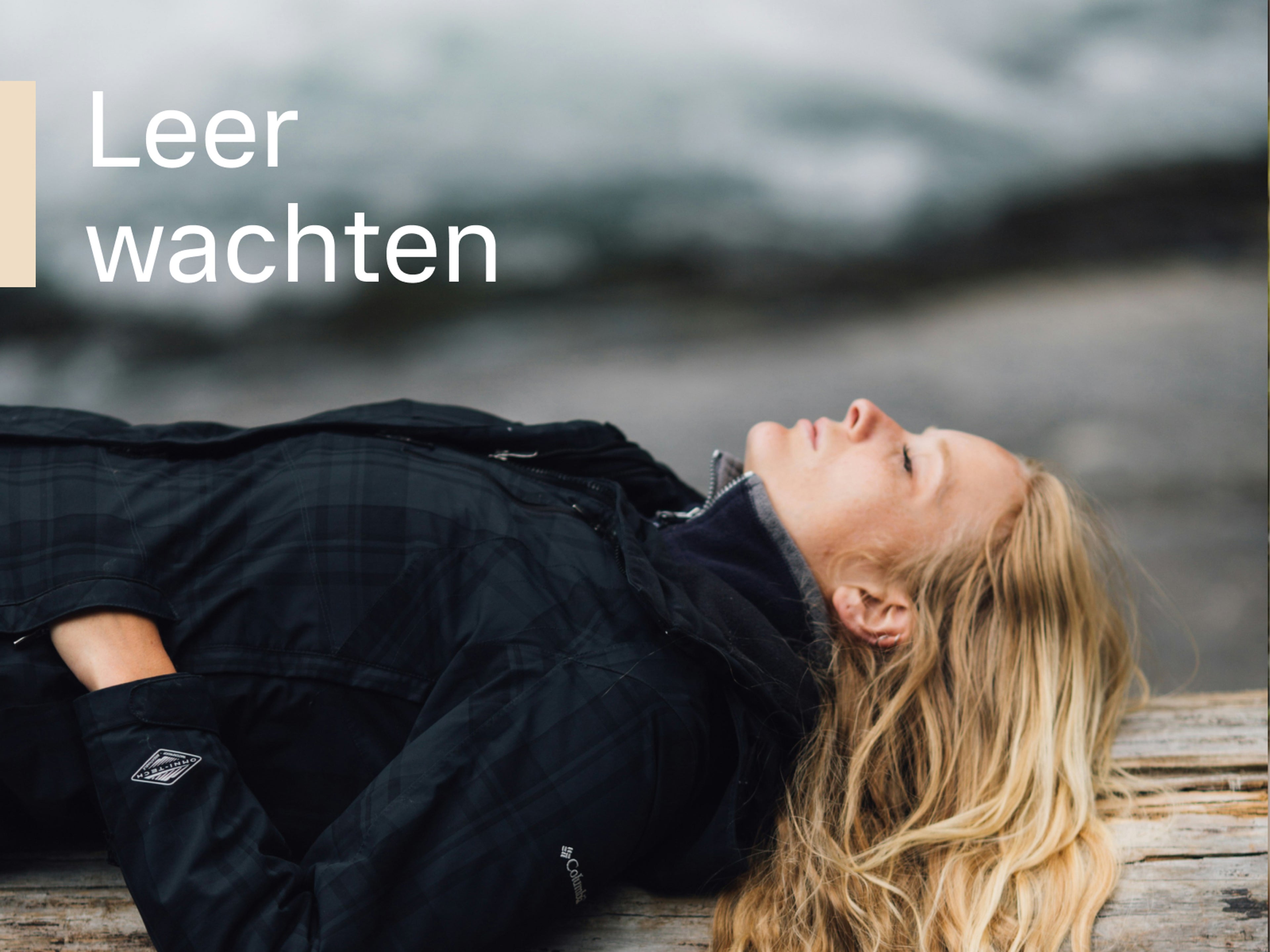 Een close-up van een vrouw die vredig op een boomstam ligt naast een stromende rivier, met een witte tekst op de voorgrond: Leer wachten.