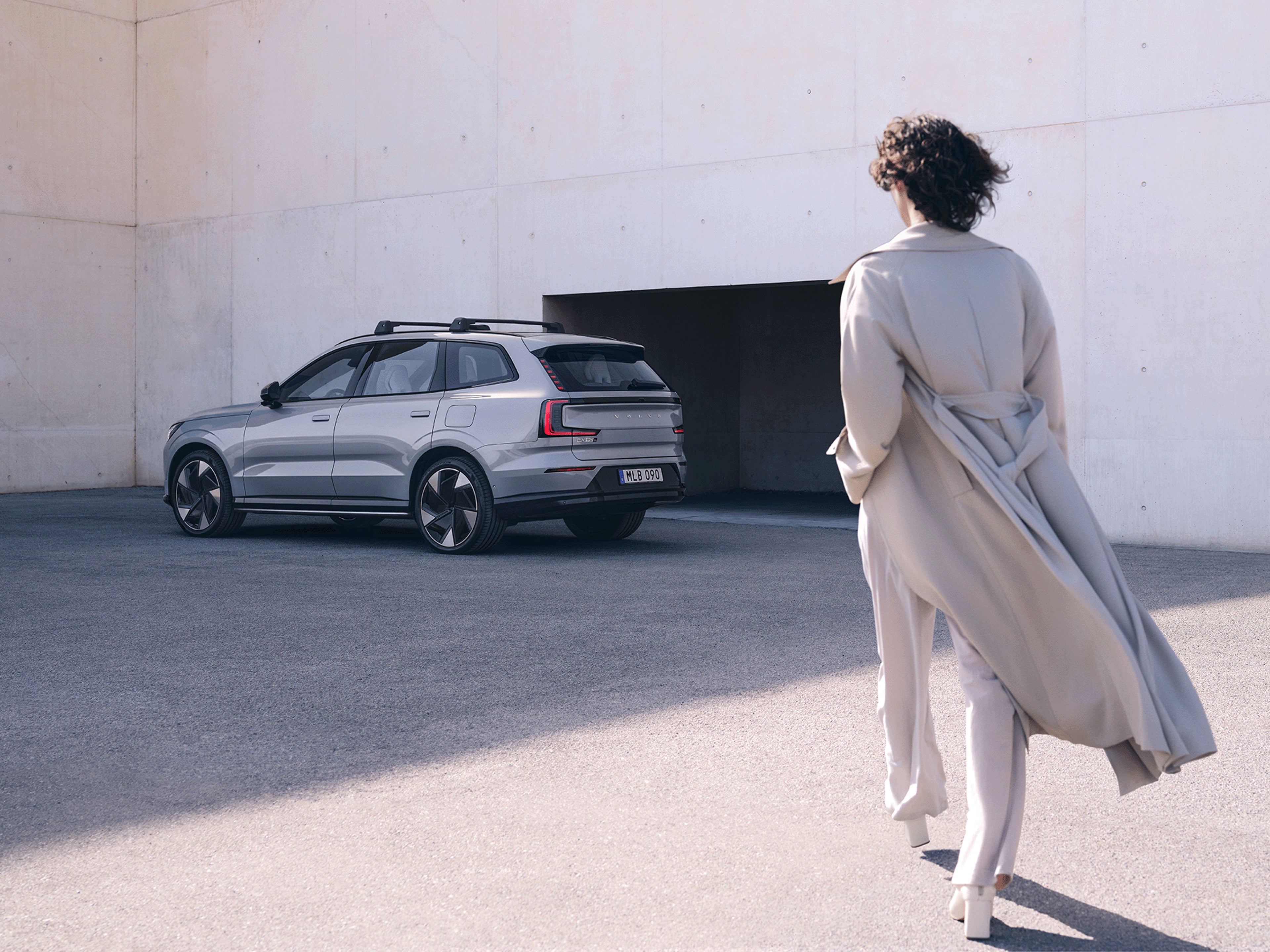 Eine Frau läuft auf einen Volvo EX90 zu.