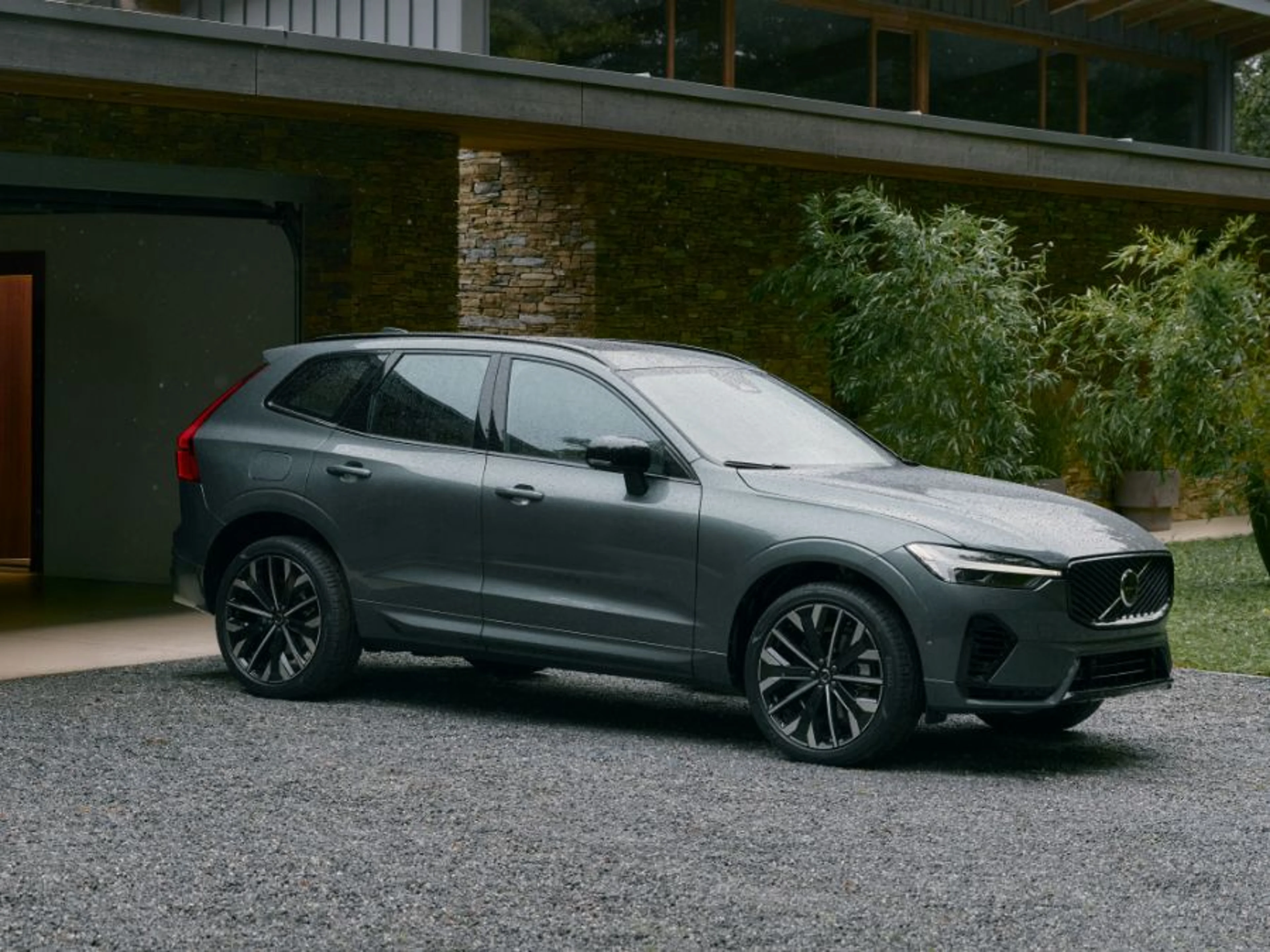 Elektrificirani Volvo XC60 SUV u elegantnoj metalik sivoj boji, parkiran u prostranom krajoliku pod nježnim svjetlom, ističući njegov pročišćeni dizajn i ekološke performanse.