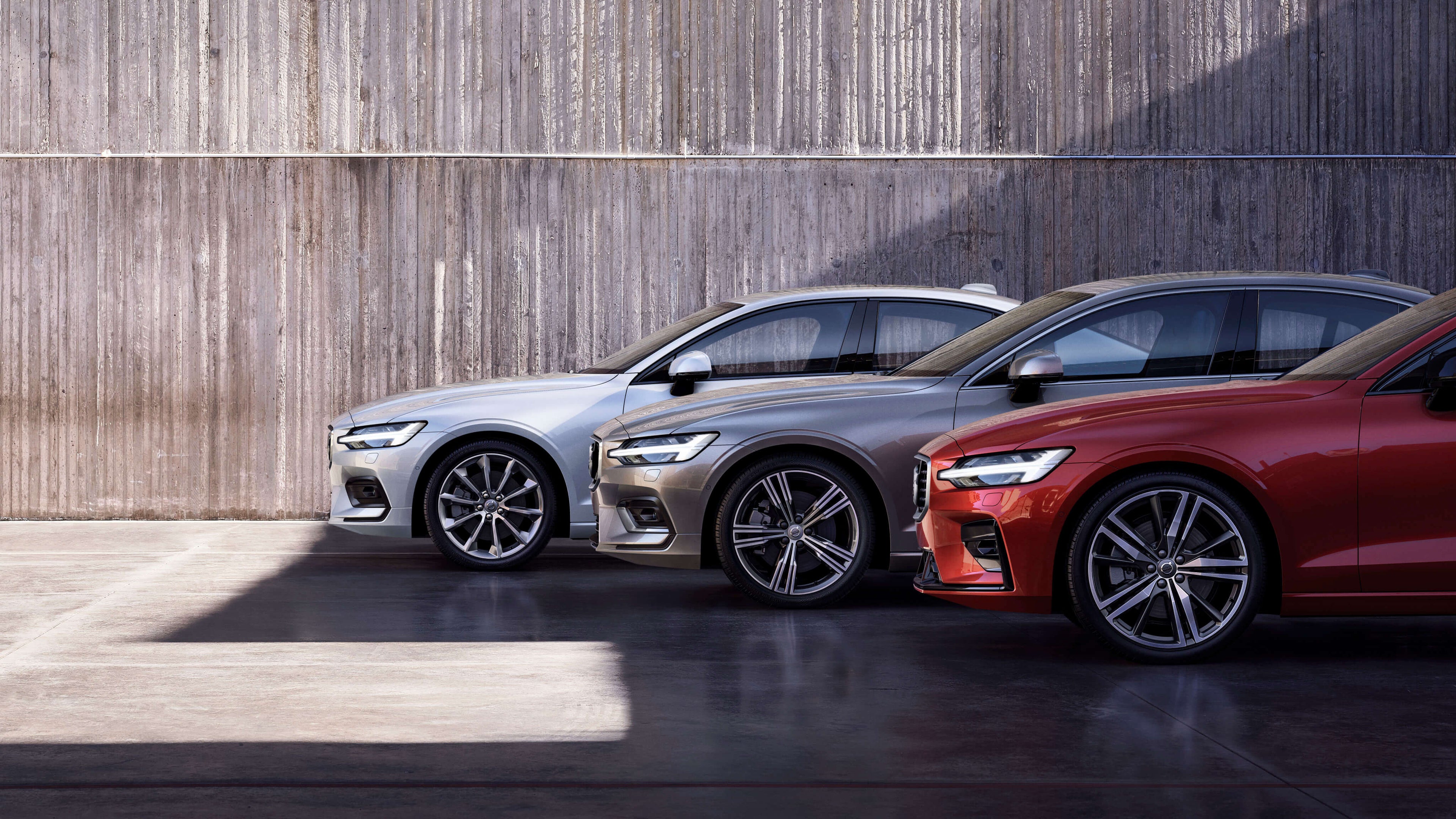 Drei Volvo Modelle stehen nebeneinander vor einer Steinwand