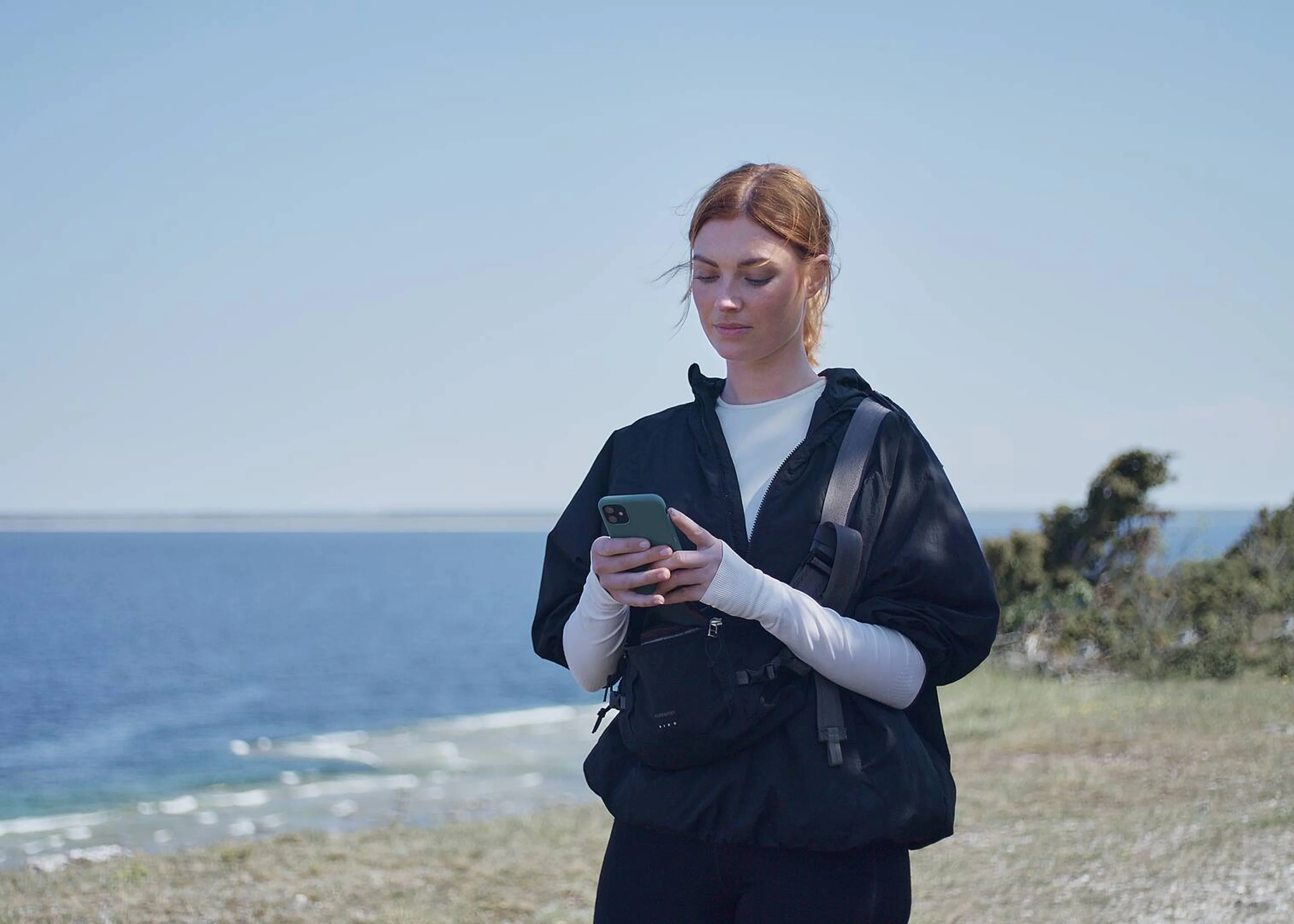 Une femme regardant son téléphone près de la mer