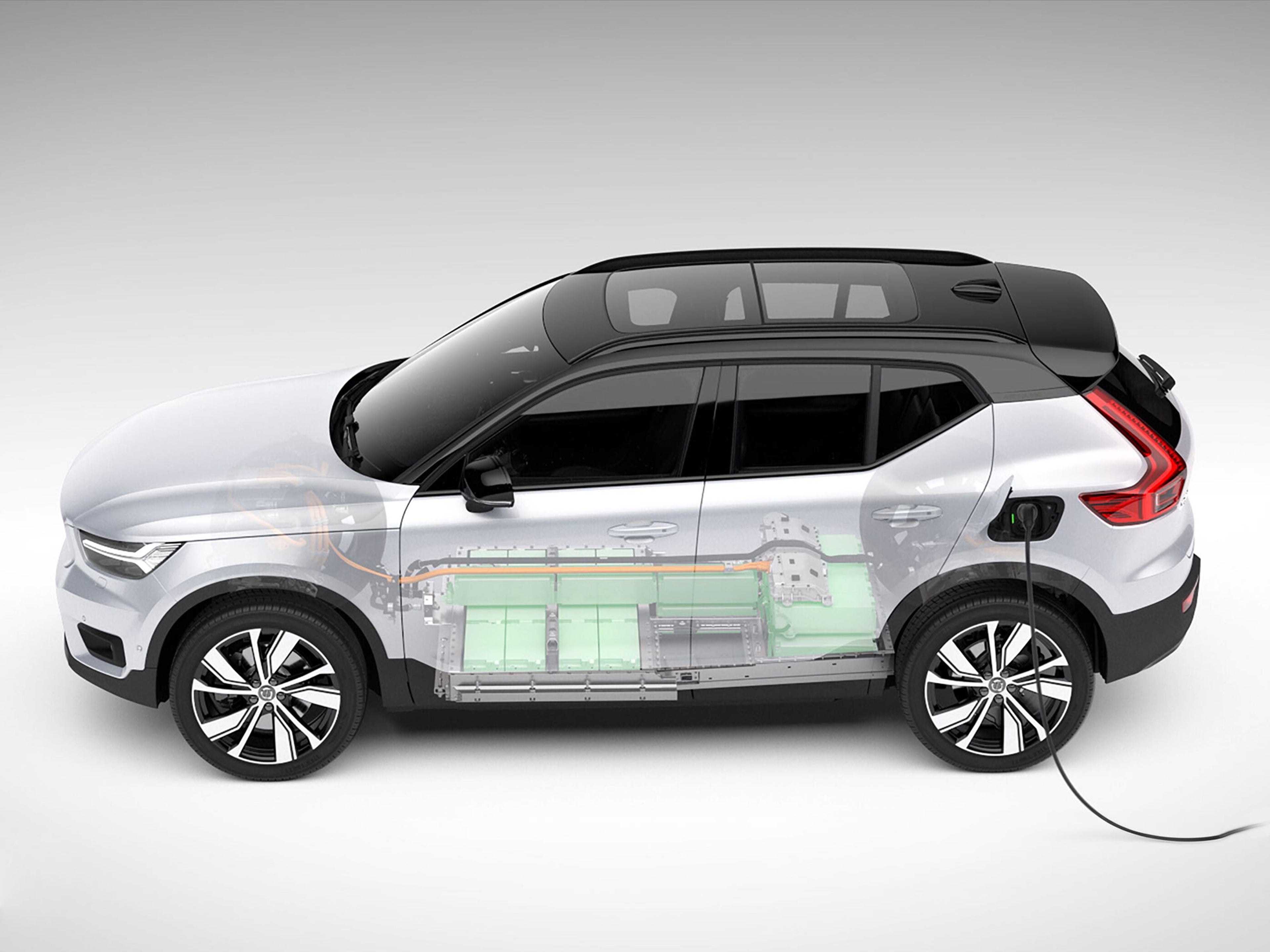 Een doorsnede illustratie van een witte Volvo XC40 Recharge die wordt opgeladen, met de batterij en interne componenten zichtbaar.