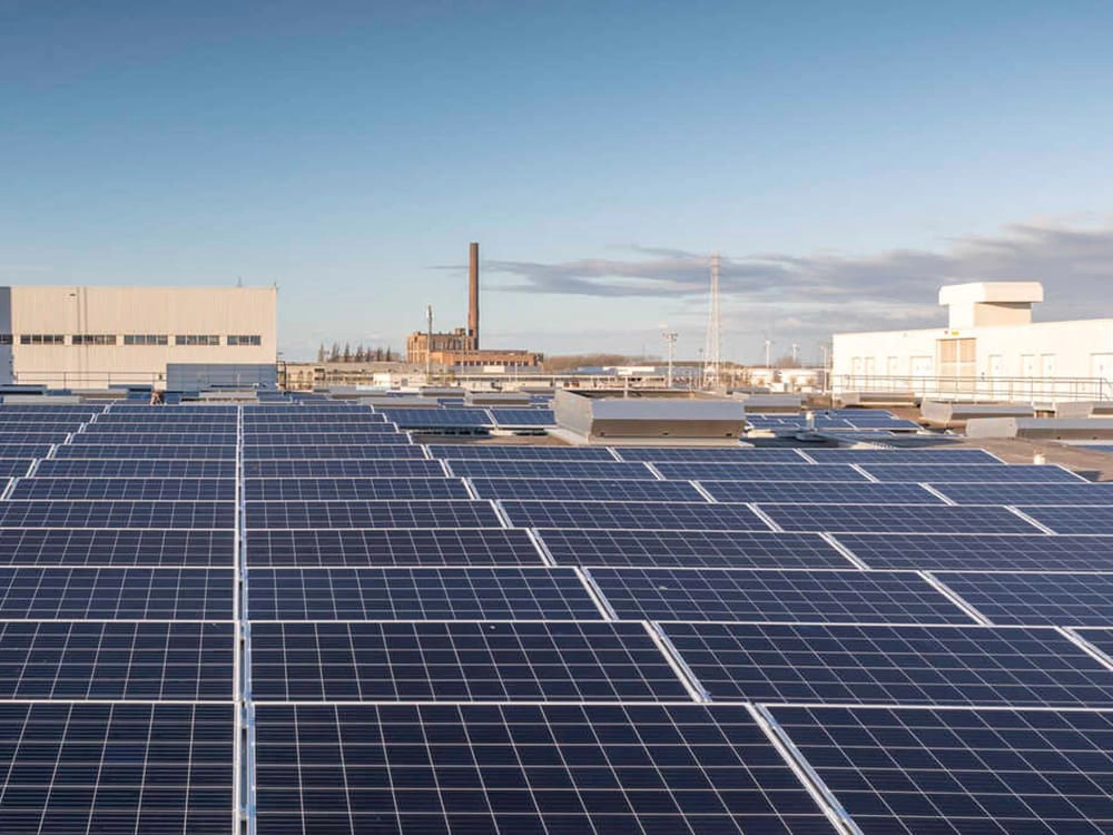 Vue aérienne de l'usine Volvo Car Gent avec des éoliennes en arrière-plan.