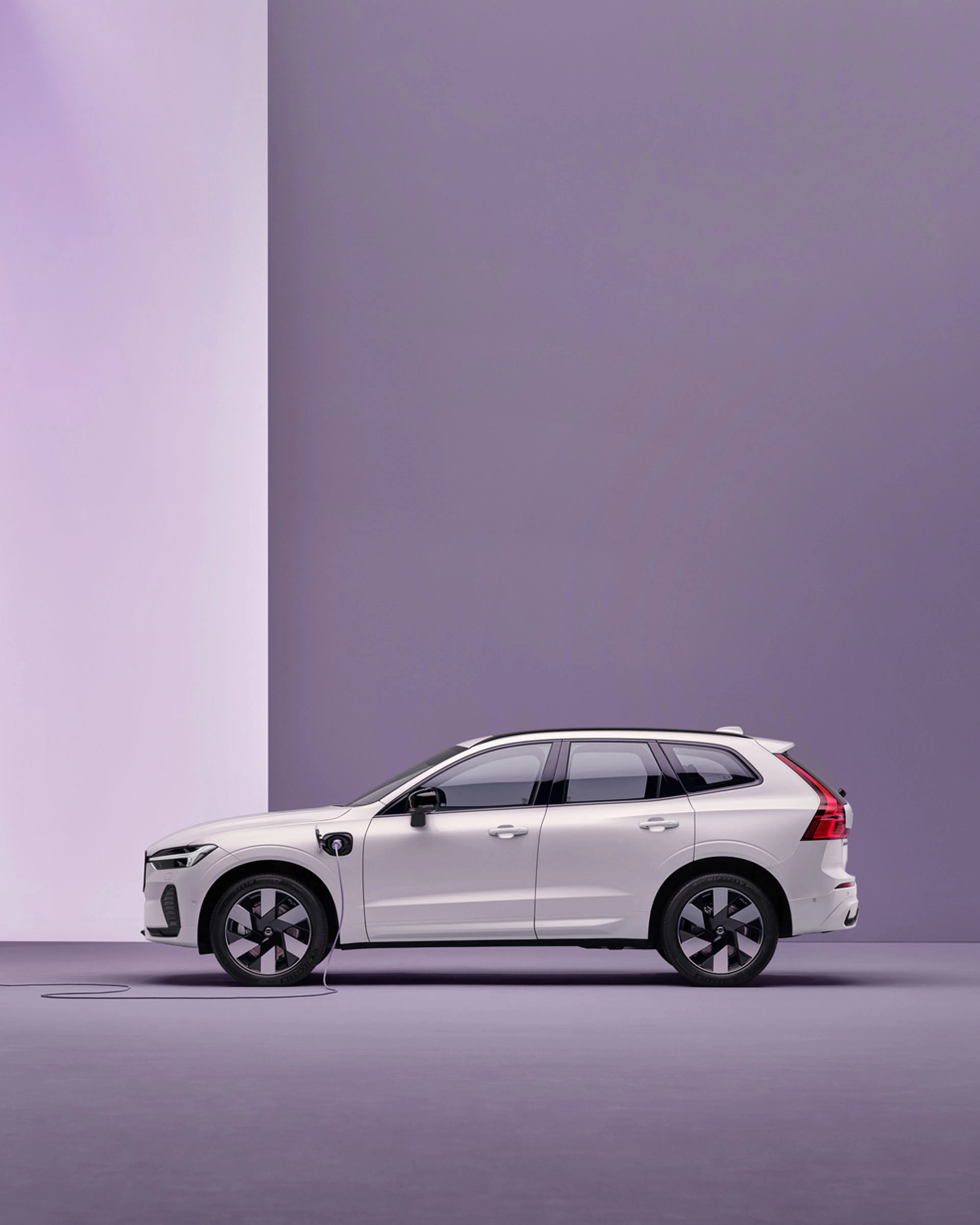 Volvo XC60 blanc branché à une borne de recharge sur fond violet