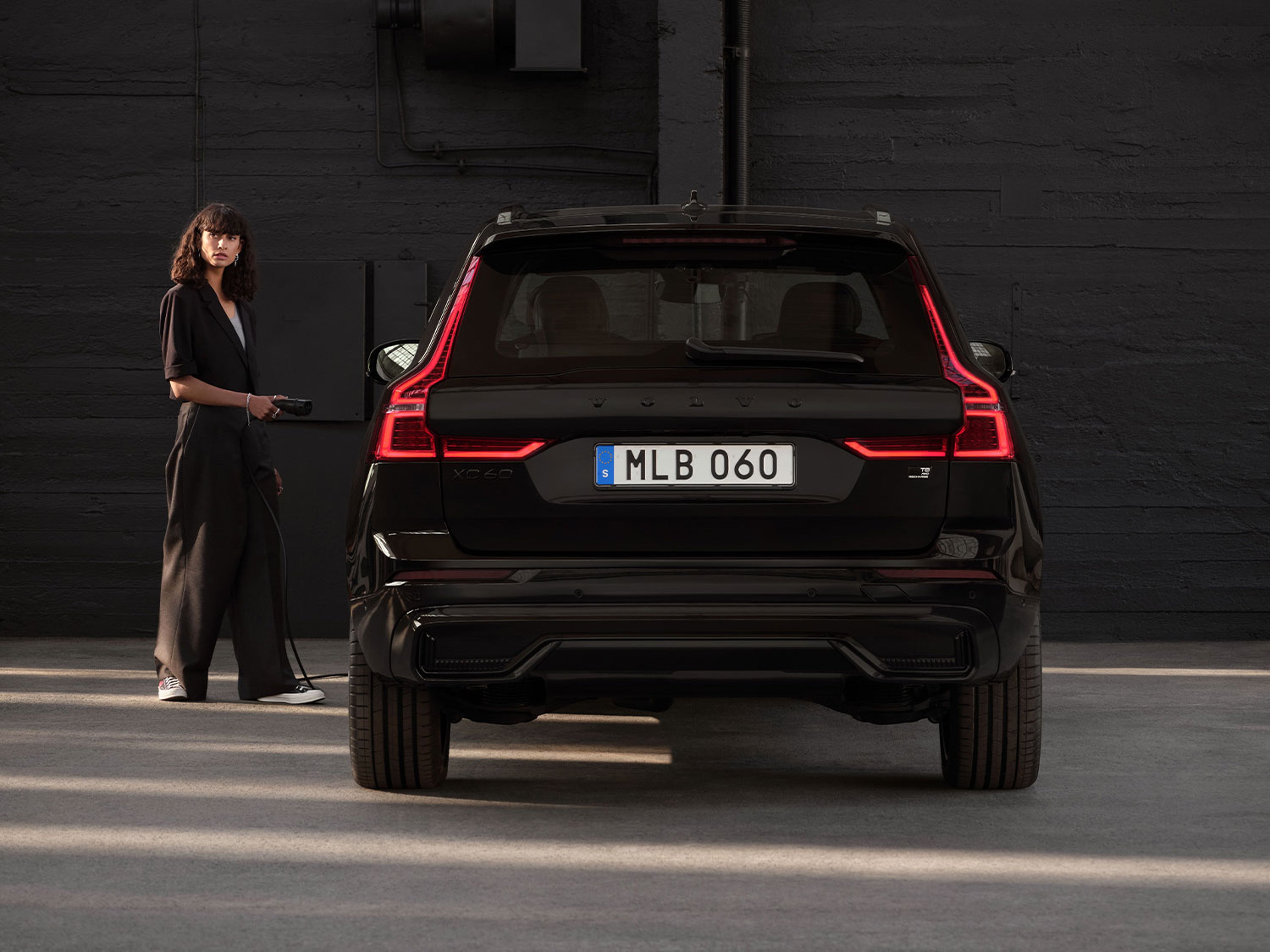 Vue arrière d'une Volvo XC40 noire, avec une personne debout à côté.