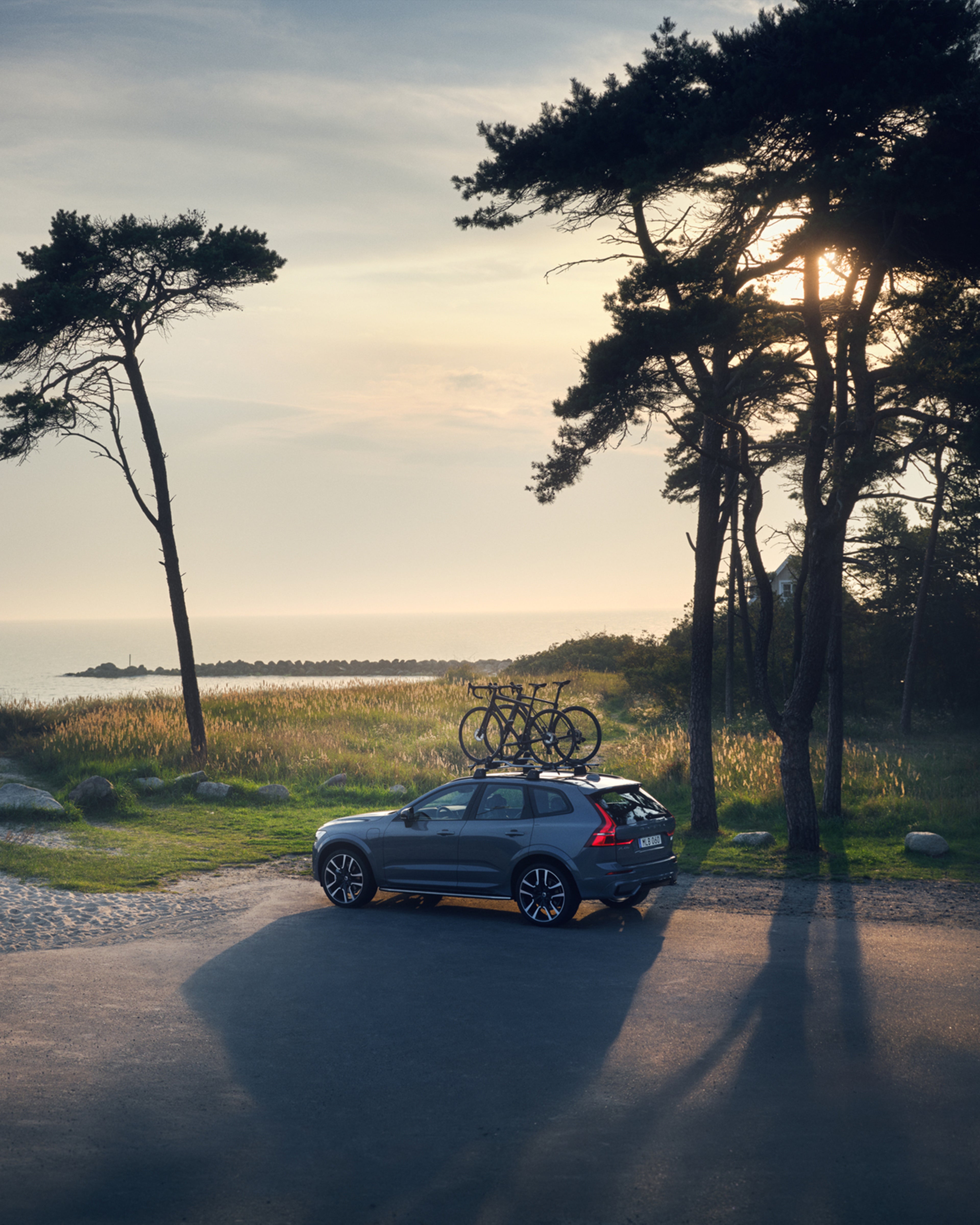 Un Volvo XC60 con portabicicletas en techo estacionado a la orilla del mar.