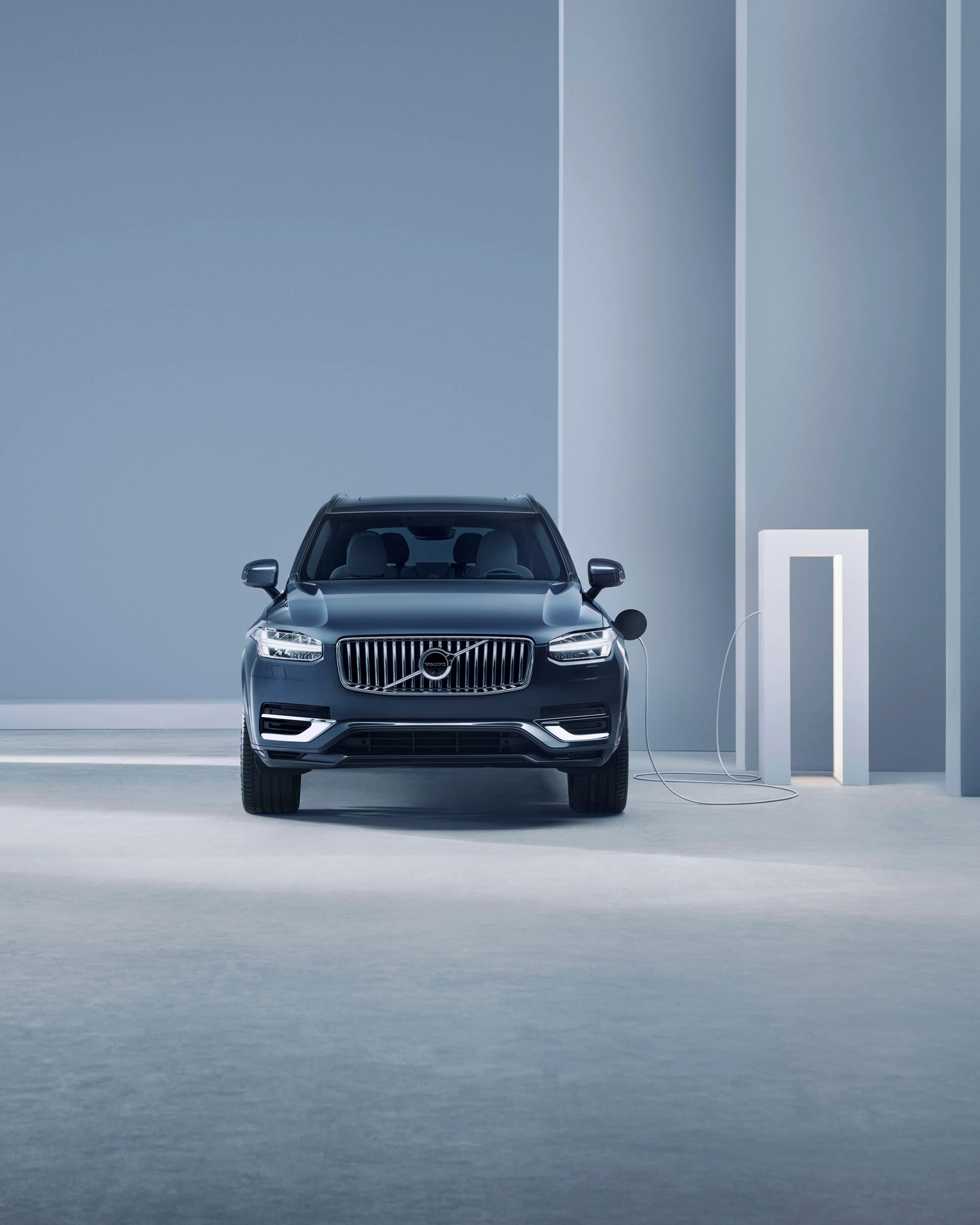 Volvo XC90 vista frontal al lado de una estación de carga