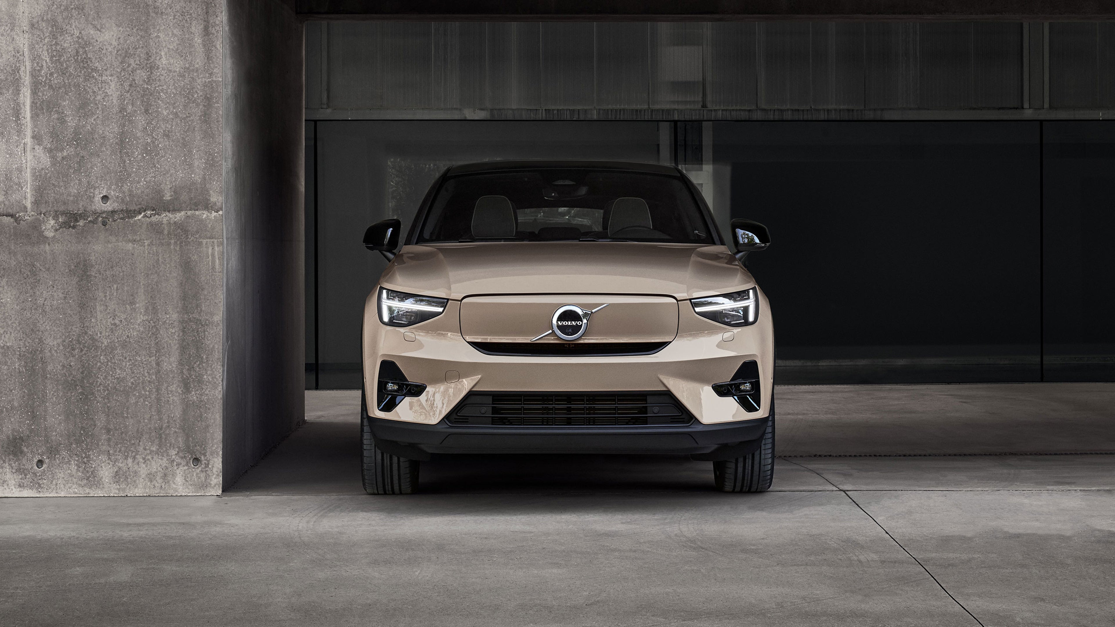 Vue frontale d'une Volvo EC40 beige stationnée dans un parking en béton moderne