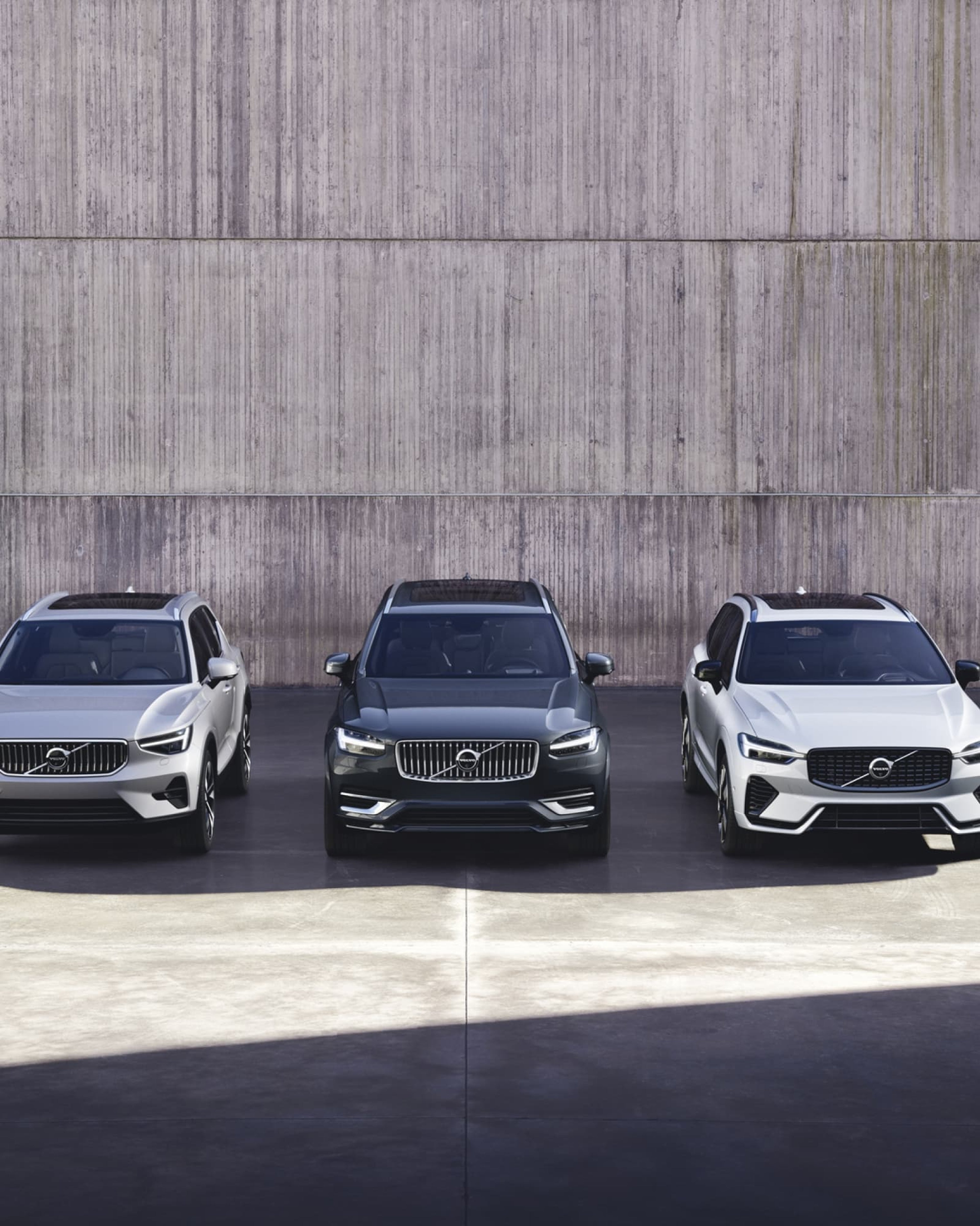Een Volvo XC40, Volvo XC90 en Volvo XC60 geparkeerd naast elkaar.