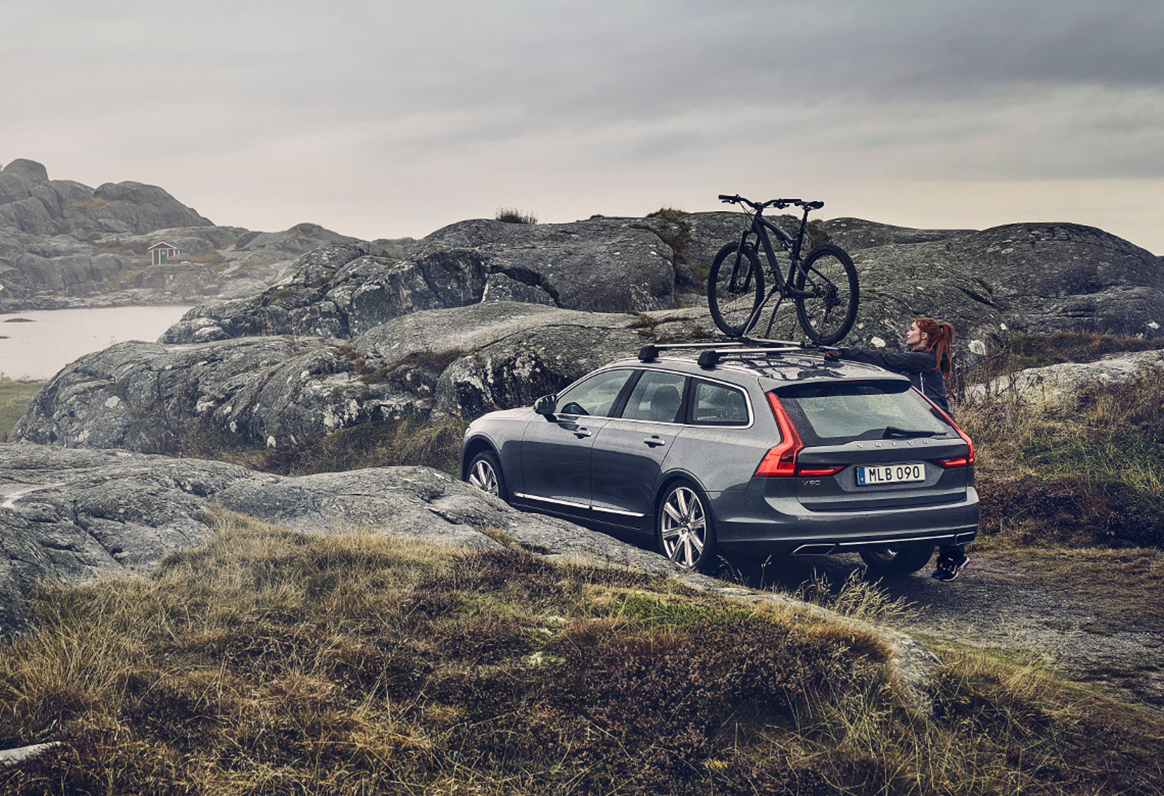 Volvo V90 CROSS COUNTRY mit Fahrradträger auf dem Dach steht in Küstenlandschaft