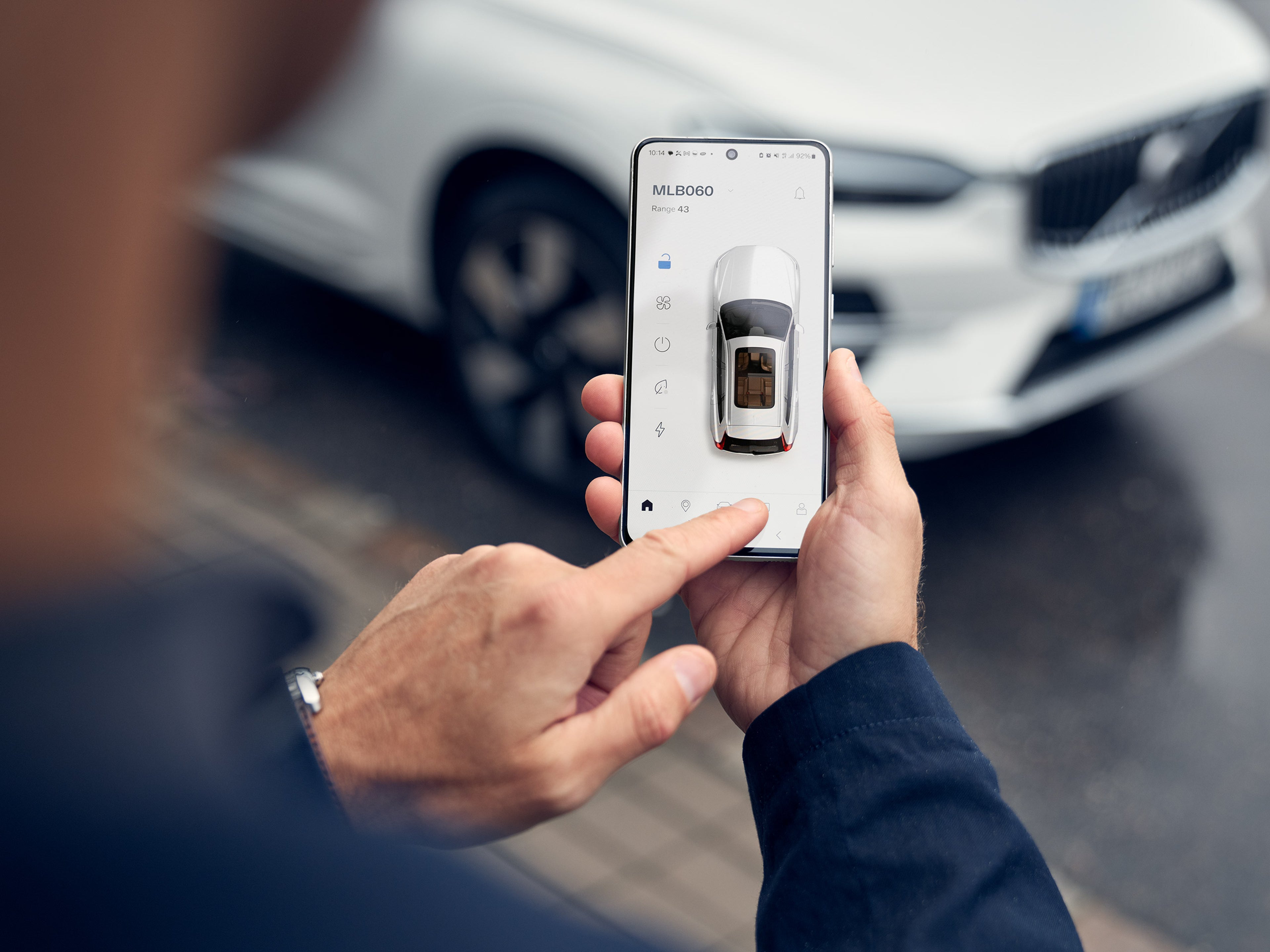 Miehen kädessä puhelin, jossa on avattuna Volvo Cars -sovelluksen näkymä.