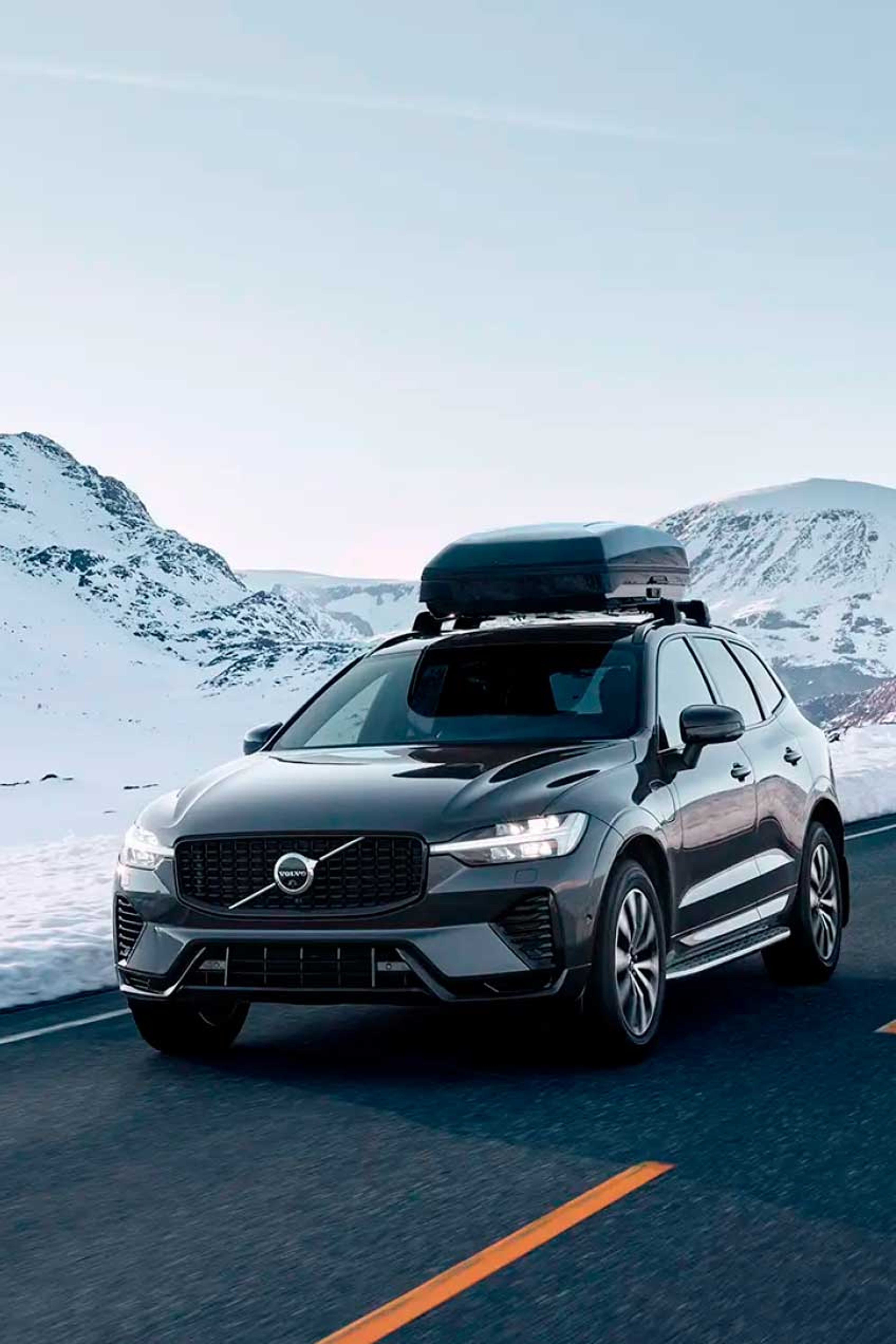 Volvo XC60 med cykelholder og cykel bagpå kører i grønne, landlige omgivelser om sommeren