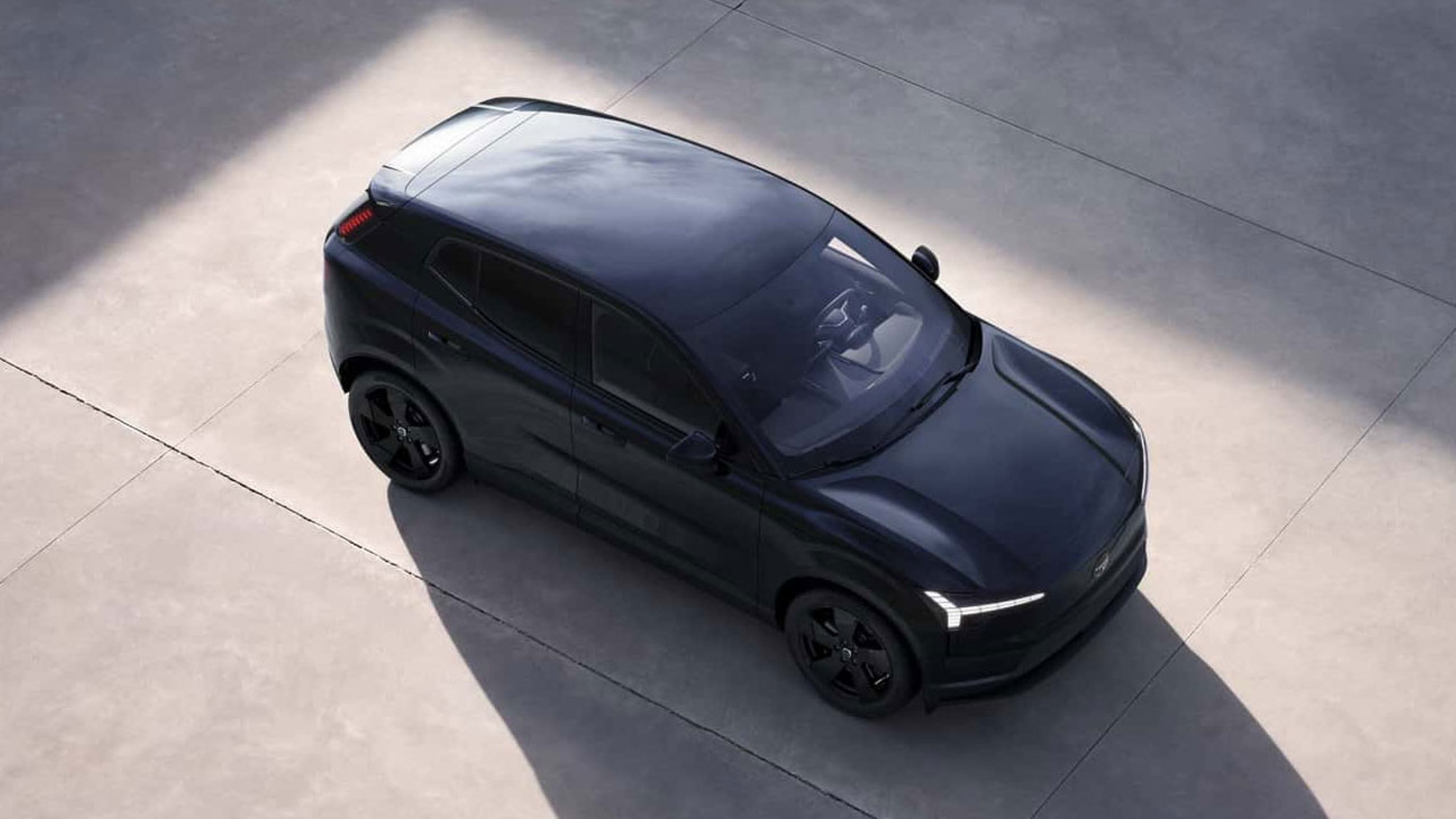 Volvo EX30 Black Edition garé dans une rue de la ville avec son emblème noir à l’avant.